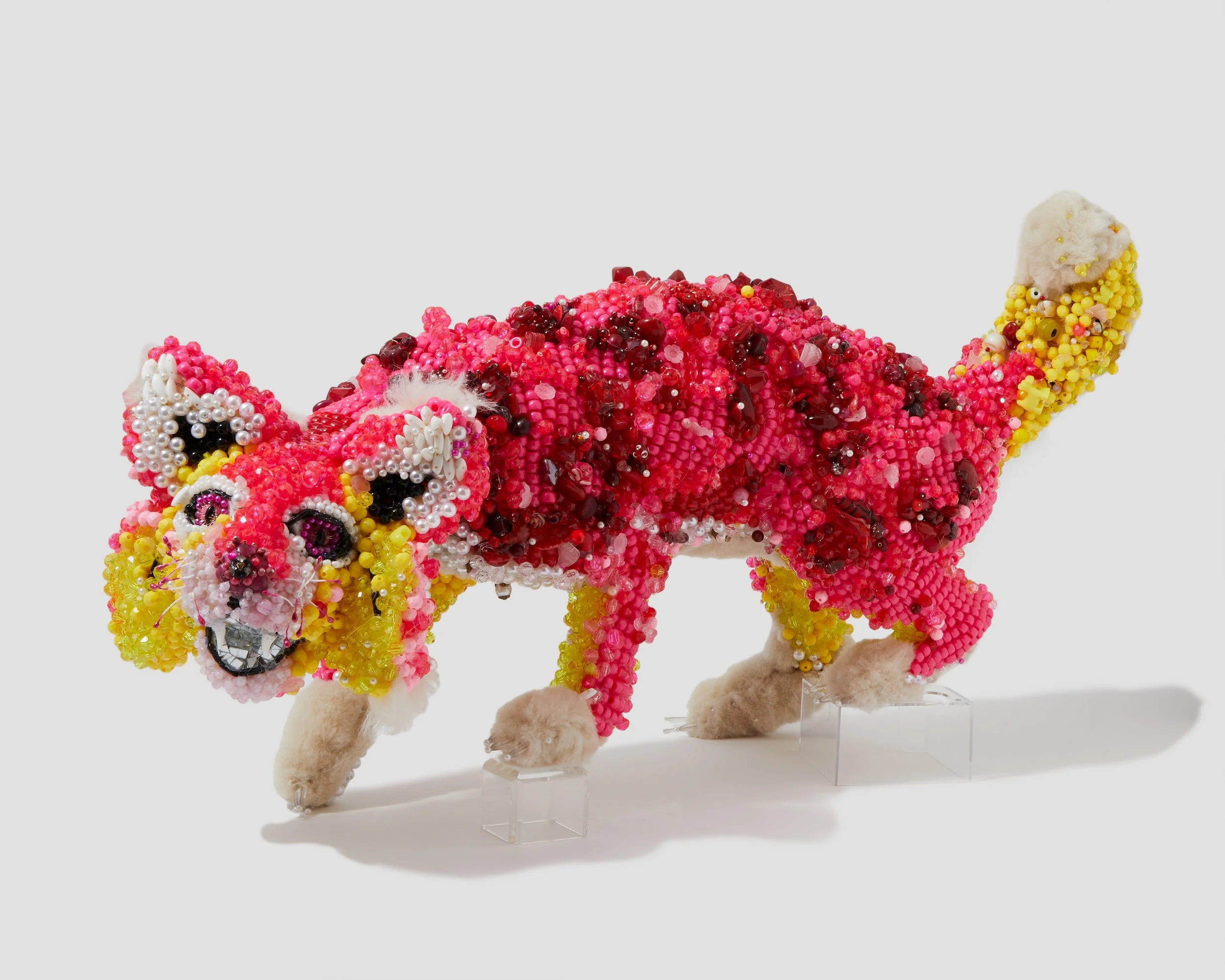 Colorful beaded sculpture of a bobcat on a white background.