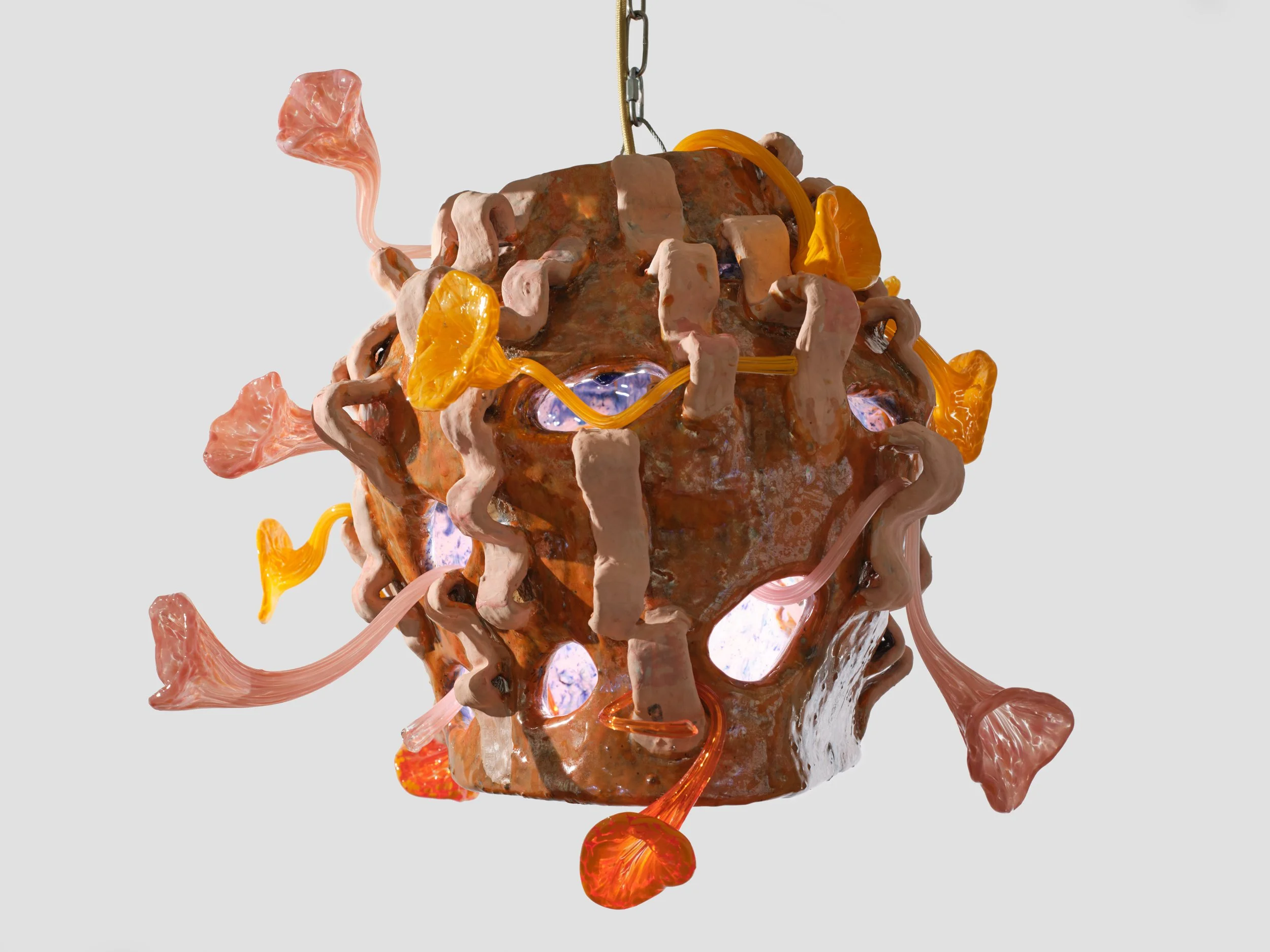 A chandelier made of colorful glass pieces including pink, orange, and purple, with a metallic chain at the top for hanging.