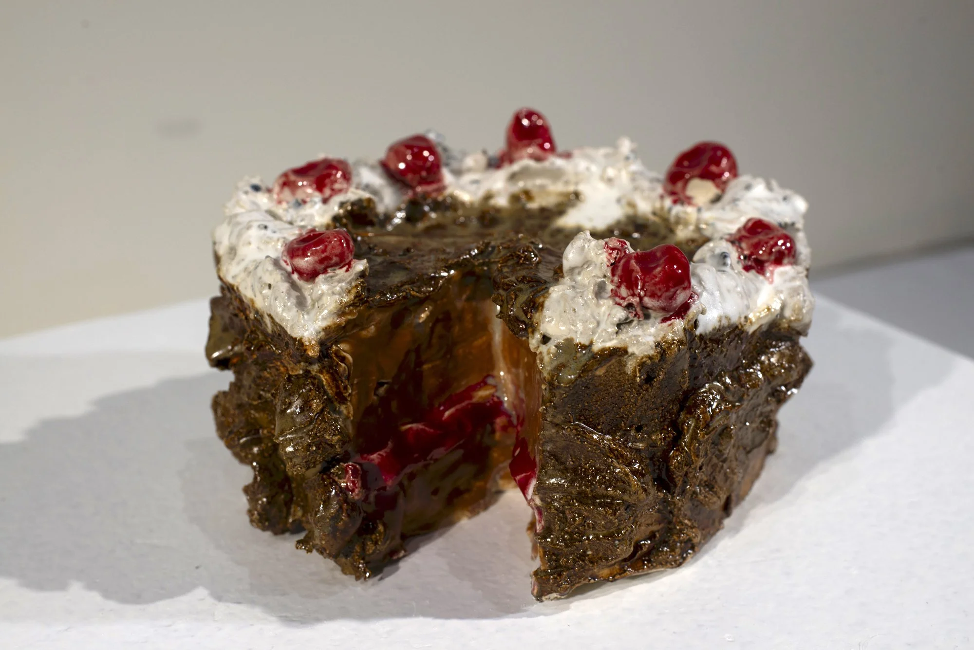 A slice of chocolate cake with whipped cream, red cherries, and chocolate syrup on top.