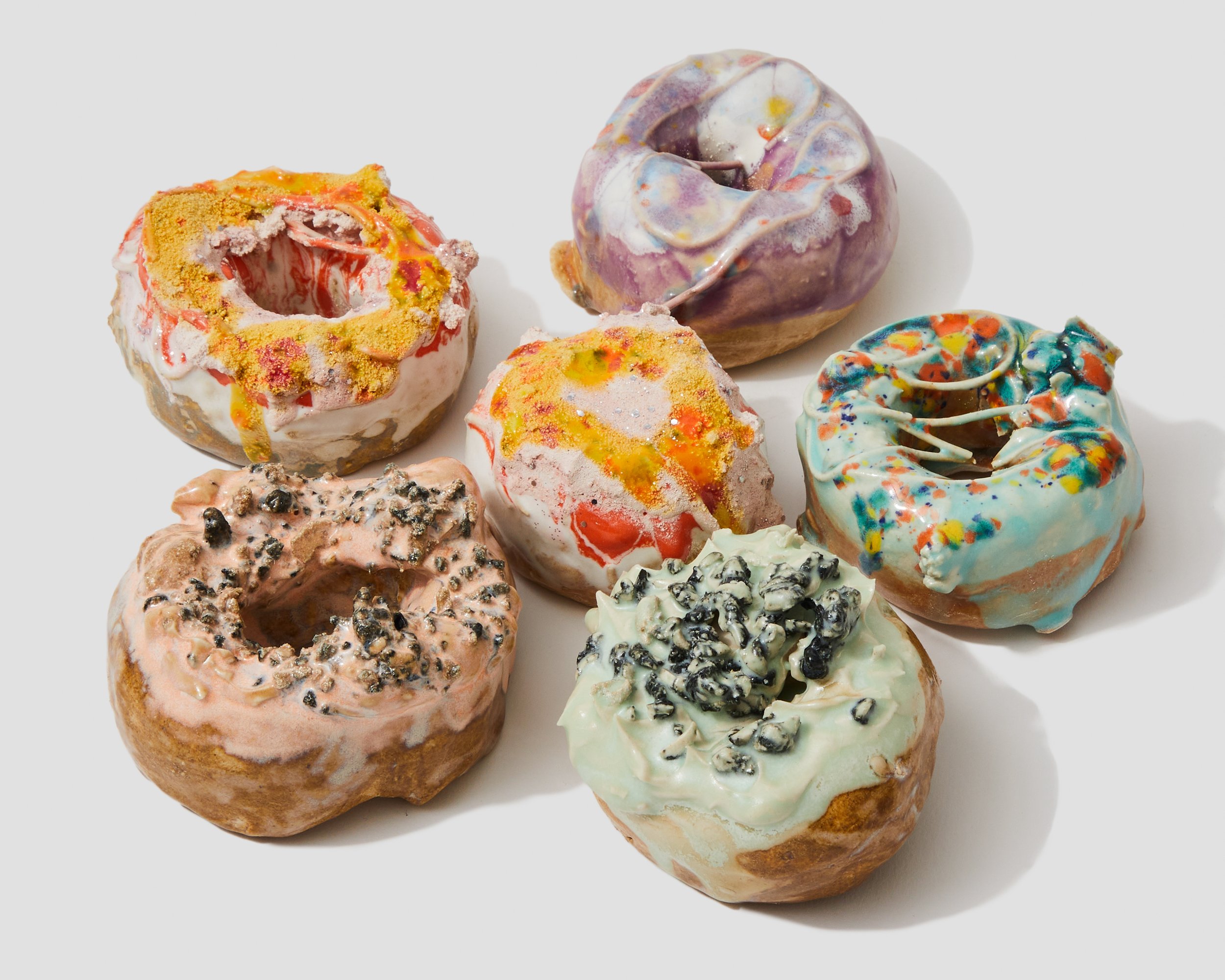Assorted colorful donuts with various toppings and glazes, arranged on a white surface.