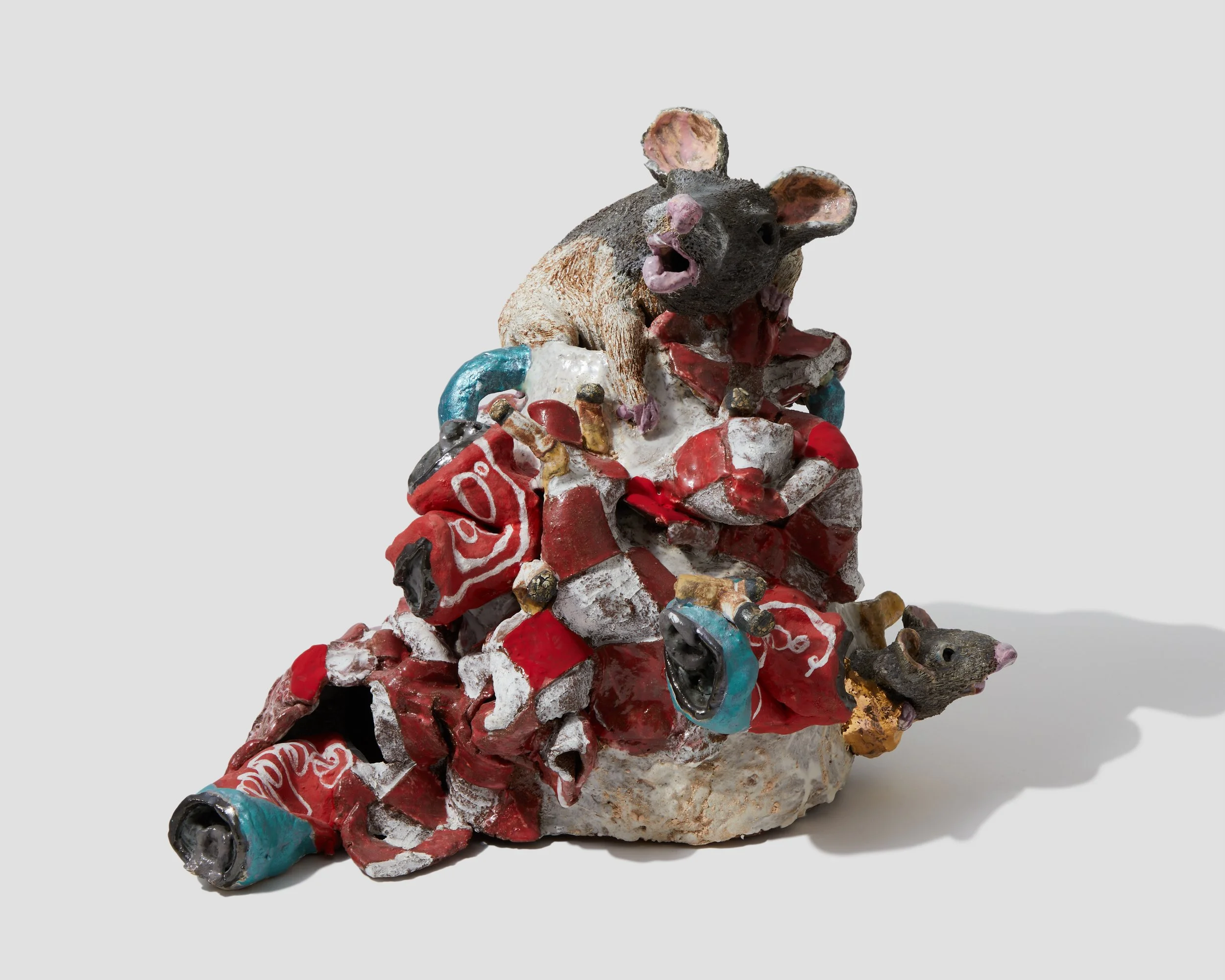 A sculpture of a rat made from various colorful materials, with its mouth open and ears perked up, sitting on a base decorated with red, white, and blue elements.