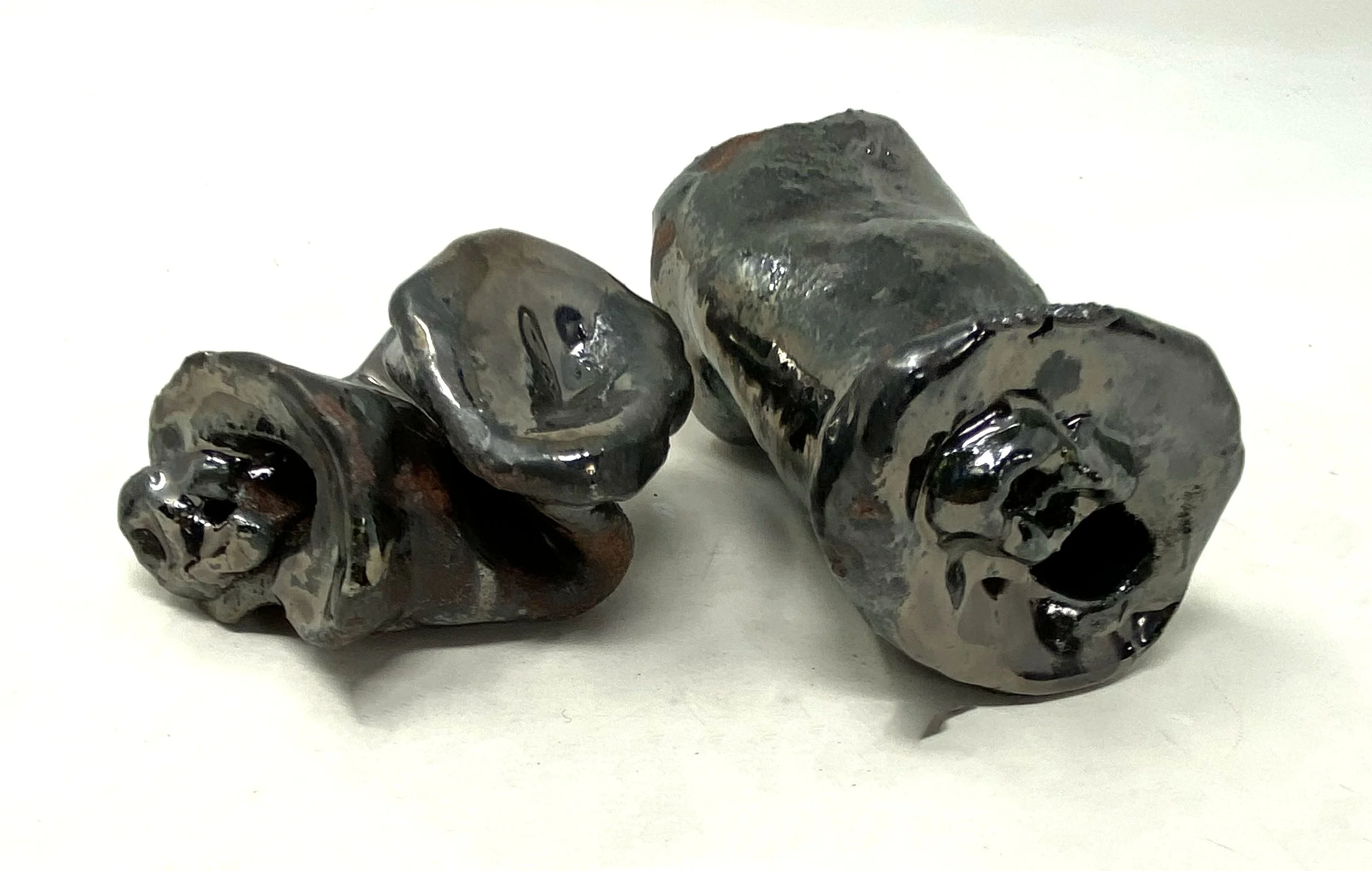 A cluster of black, brown, and gray glossy cans on a white surface.