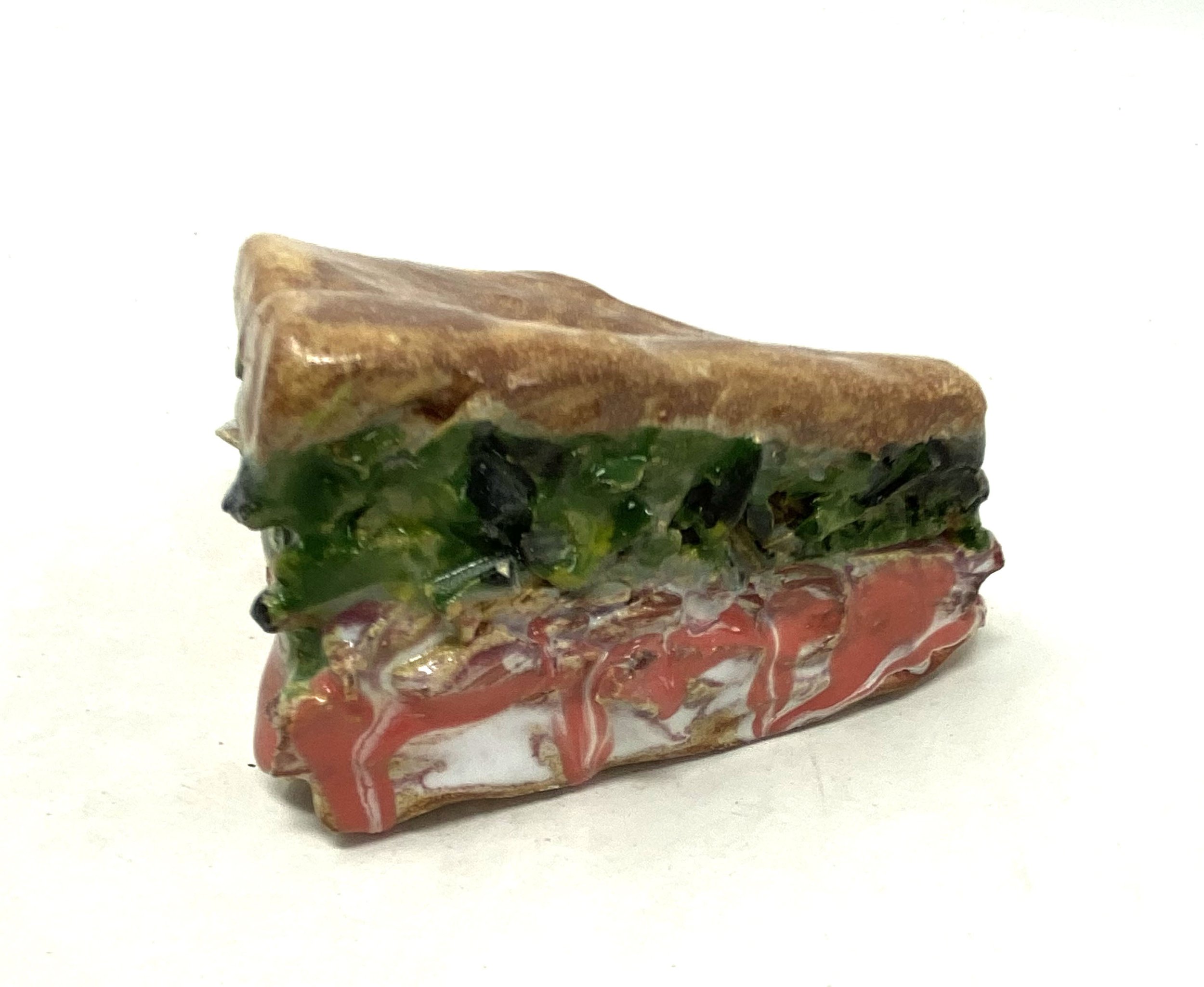 A colorful sandwich with a layered design, featuring green, black, and reddish-brown colors.