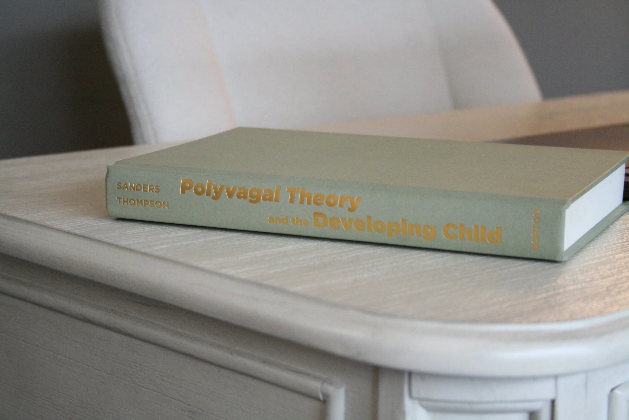 A hardcover book titled 'Polyvagal Theory and the Developing Child' by Sanders Thompson resting on a white wooden surface.