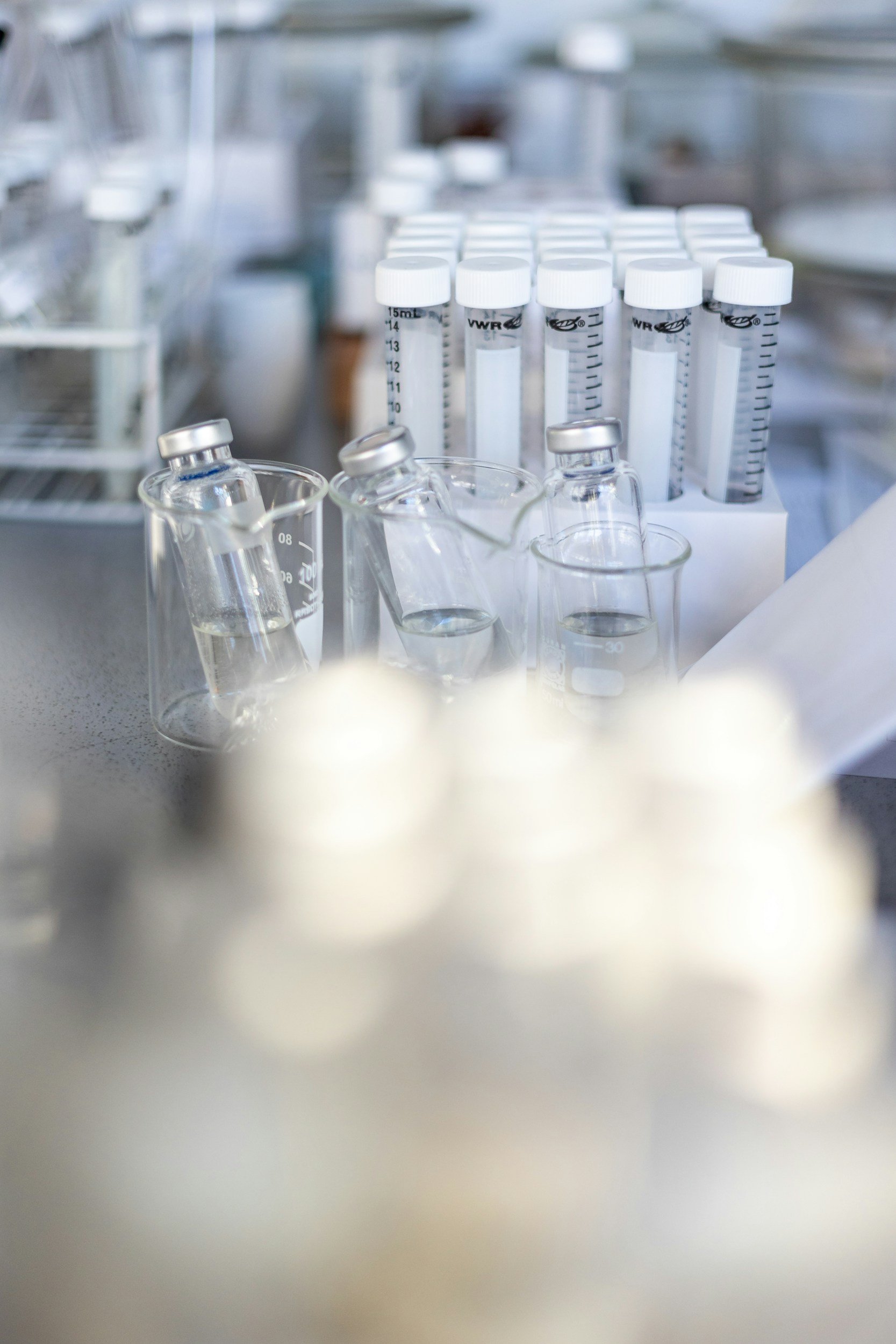 Several glass test tubes and vials are arranged on a counter in a laboratory setting.