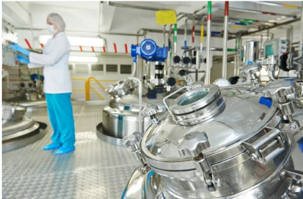 A scientist in a laboratory wearing blue scrubs, working with scientific equipment and machinery.
