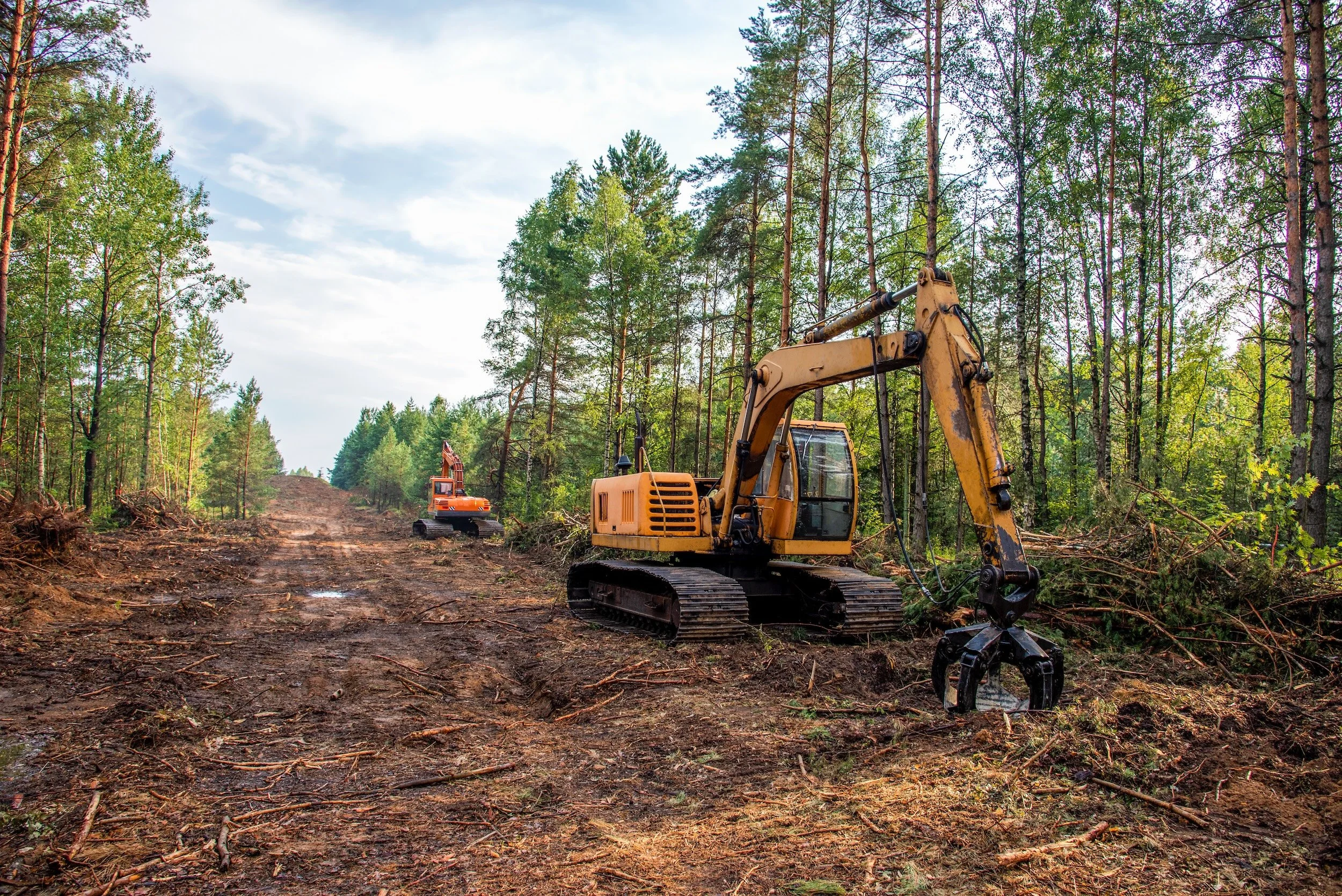 Two excavators clearing land and preparing a North Carolina construction site for development.
