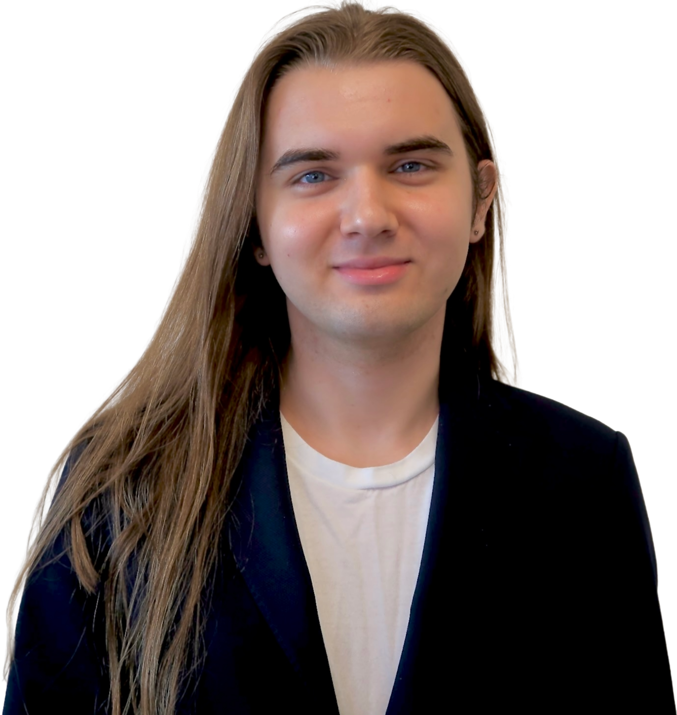 A young man with long, straight, blonde hair and blue eyes, wearing a black blazer over a white shirt, smiling slightly, against a blurred background.