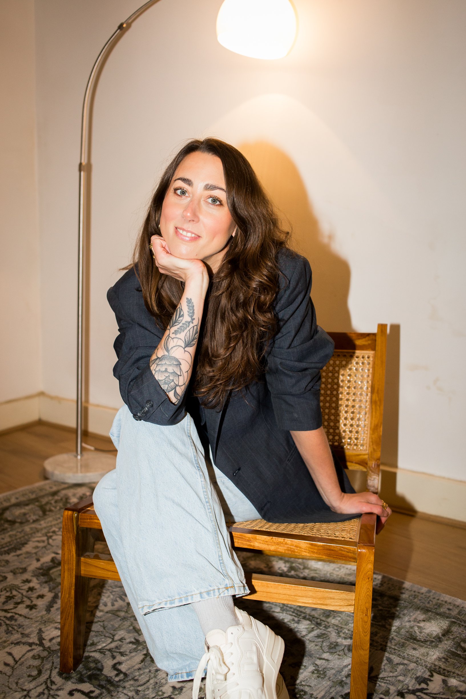 ADHD Coach sits on a chair looking and smiling at the camera with ease