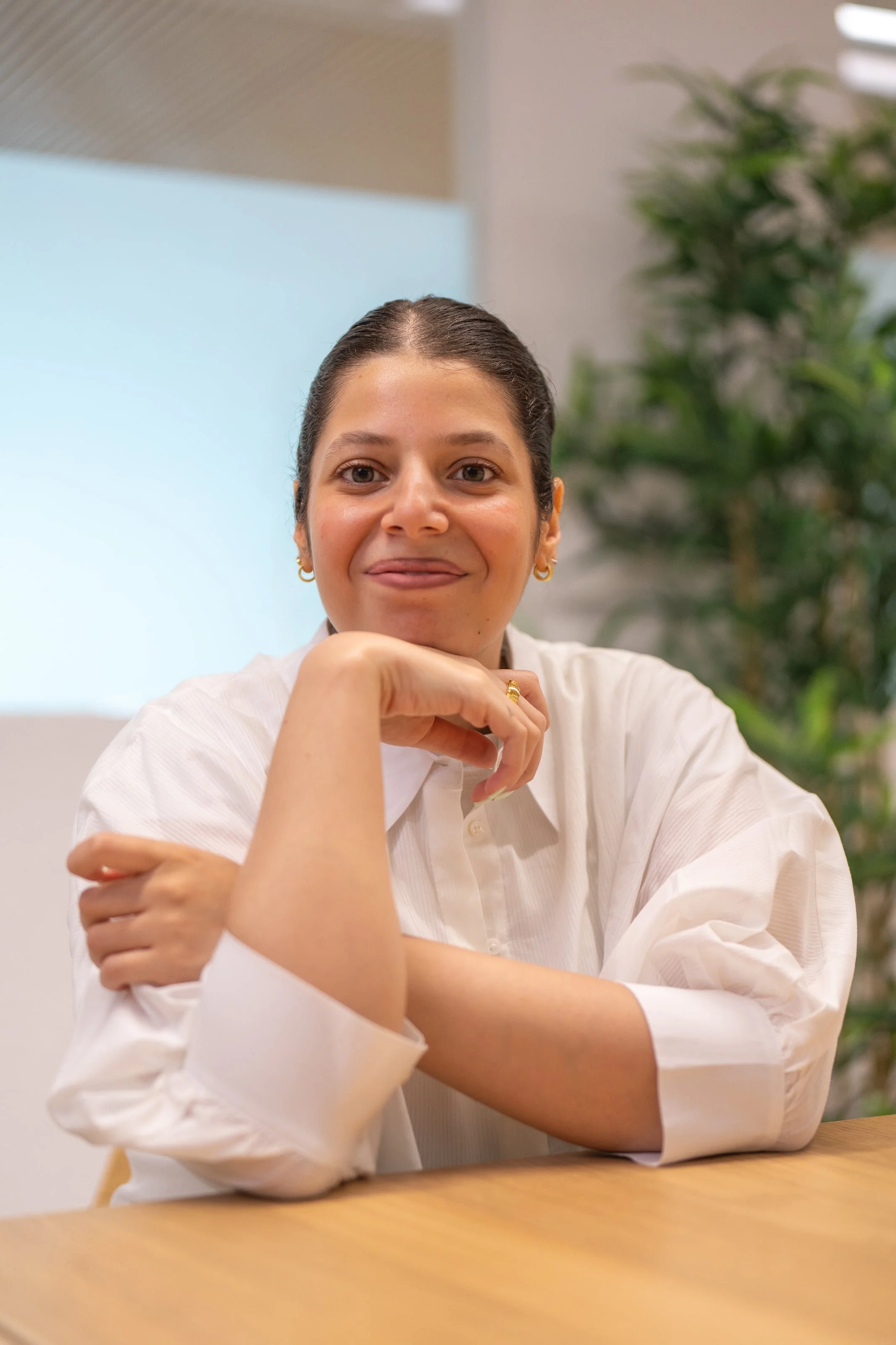Sarah Farrag, a psychosocial counsellor in Geneva, seated at a table and smiling at the camera.