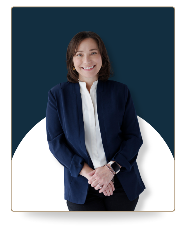 Farrah Christos, LCSW, LISW and licensed therapist, smiling while standing in a white studio wearing a white blouse and navy blazer