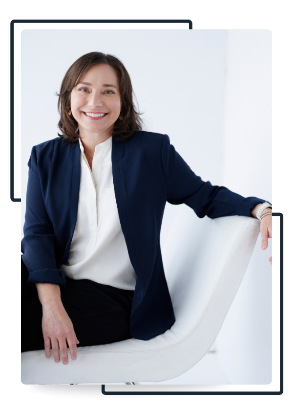 Farrah Chrstos, LCSW, LISW sitting on a chair against a white background, wearing a navy blazer and smiling.