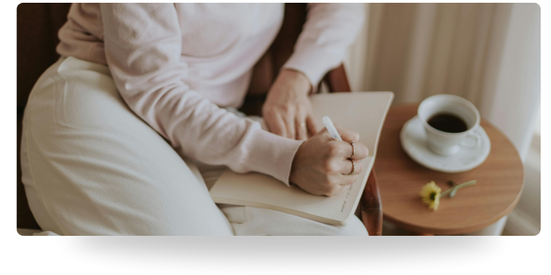 Person journaling with coffee during a moment of reflection, representing therapy for overwhelmed, high-functioning individuals