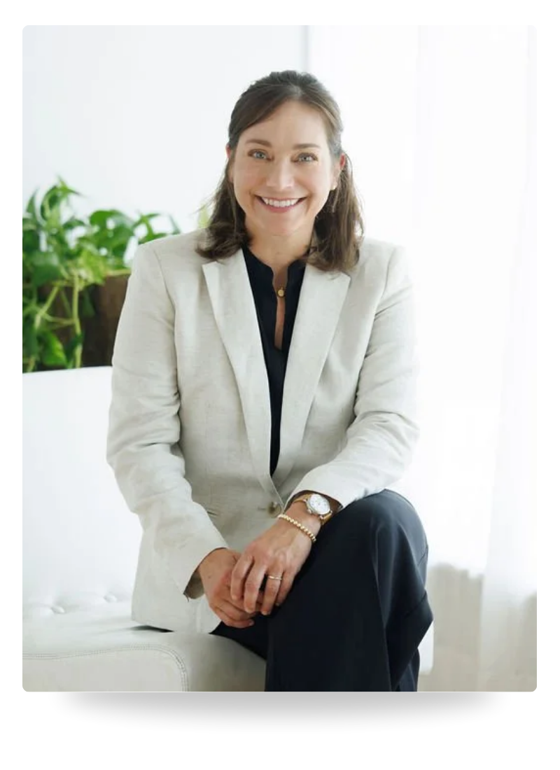 Farrah Chrstos, LCSW, LISW sitting on a white sofa wearing a beige blazer and smiling.