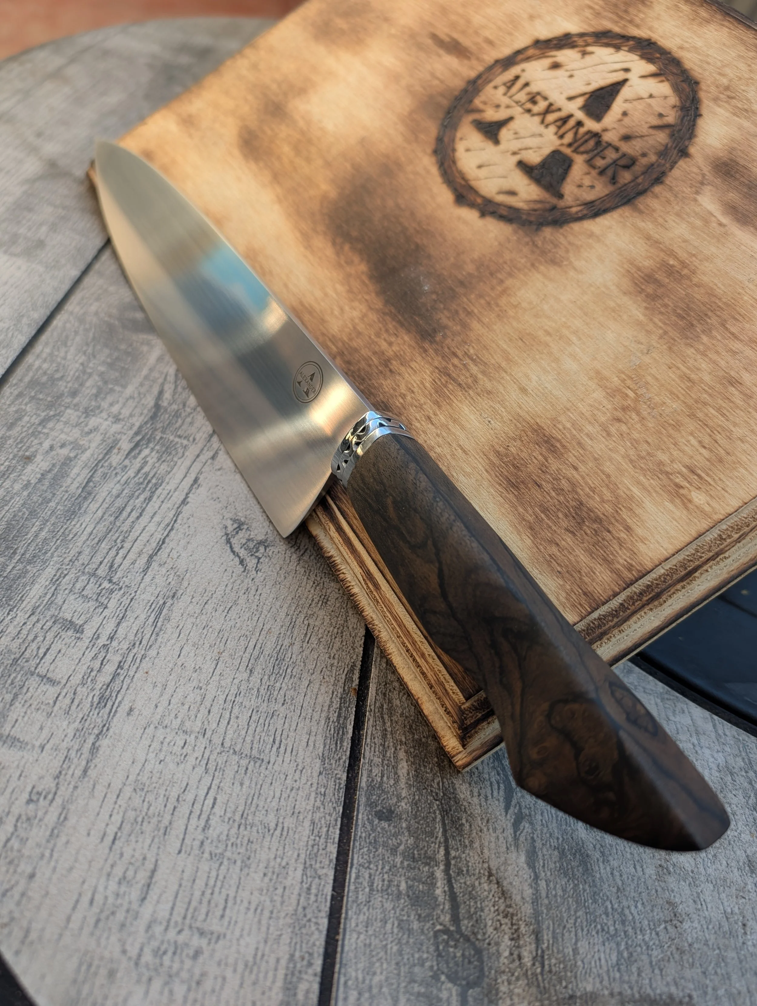 close-up of a wooden cutting board with a branded logo and a hunting knife with a black handle resting on it