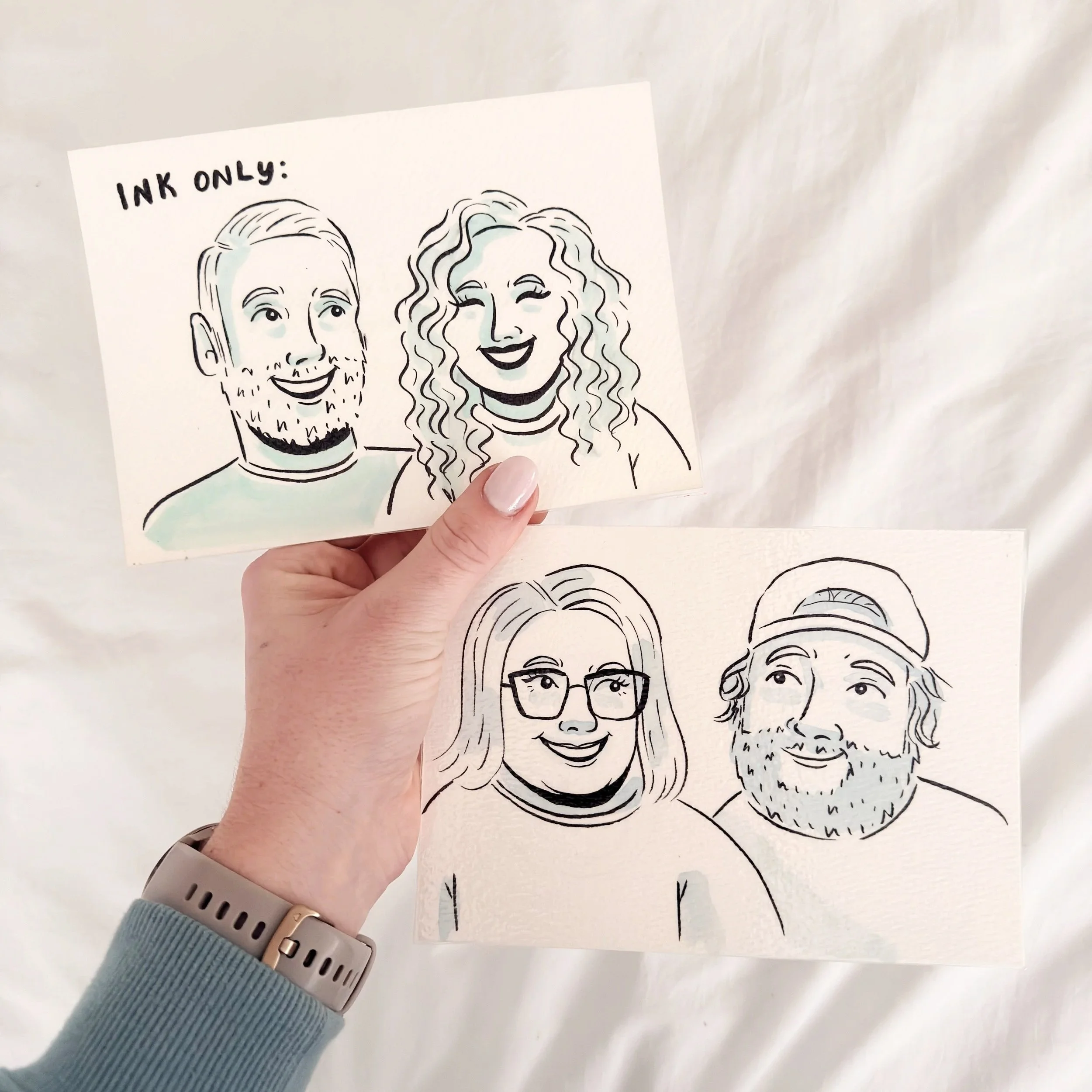 Drawing of two smiling people's faces, one with short hair and a beard, and the other with curly hair and glasses, held by a person with a light blue sweater and a beige watch.
