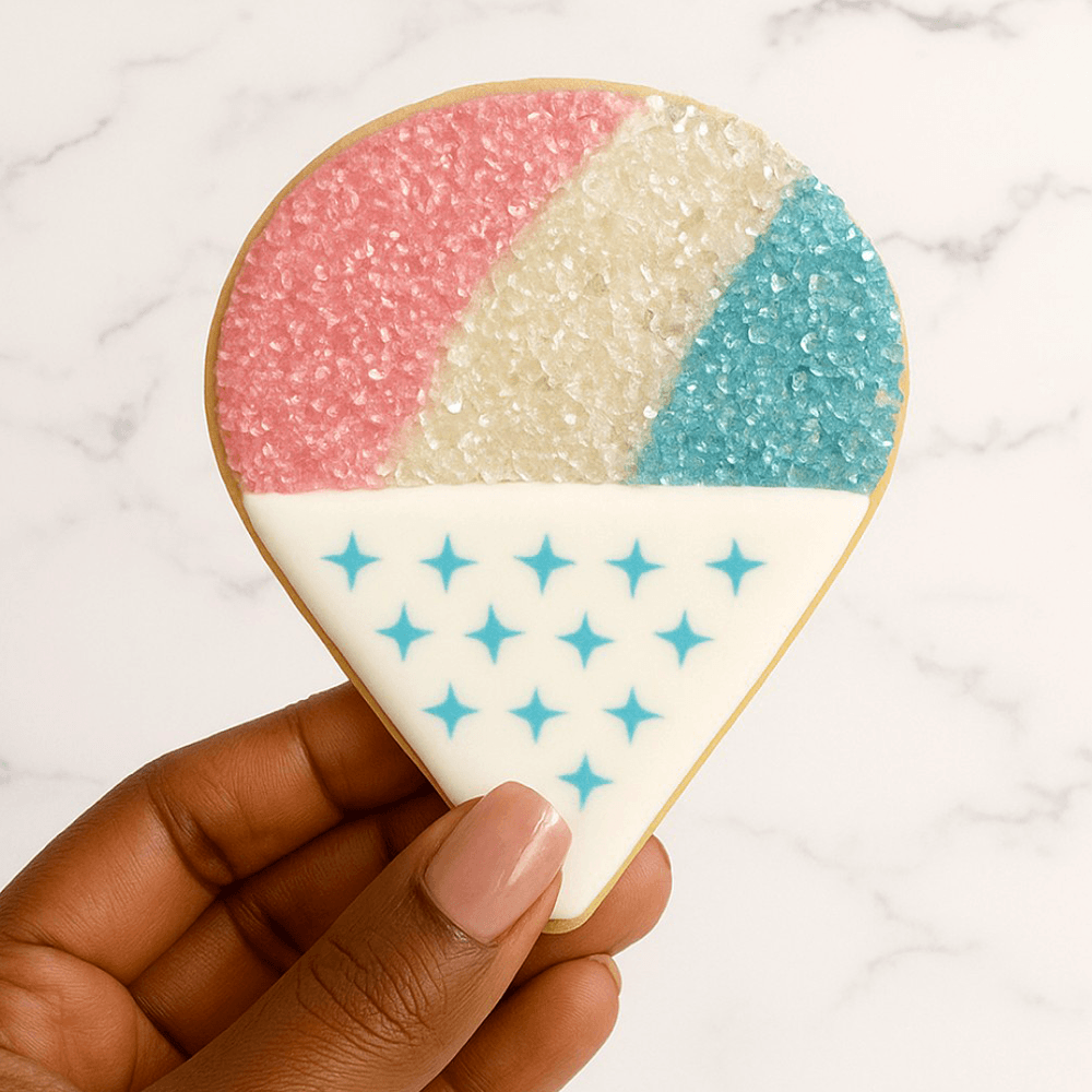 Decorative ice cream-shaped cookie with pink, white, and blue sugar toppings and blue star patterns.