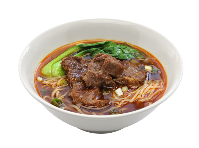Bowl of Asian beef noodle soup with beef chunks, leafy greens, and noodles in broth.