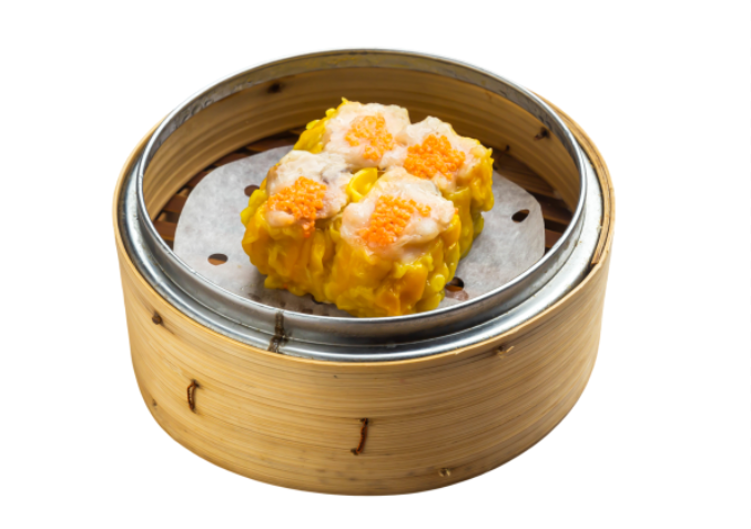 Steamer basket with two vegetable dumplings inside, lined with parchment paper.