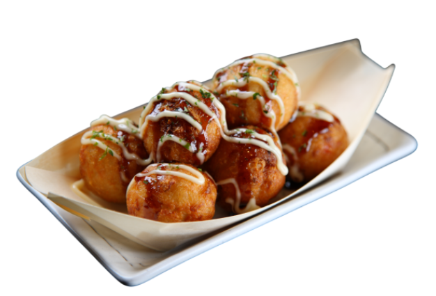 A white rectangular dish filled with takoyaki balls drizzled with mayonnaise and sauces, garnished with green herbs