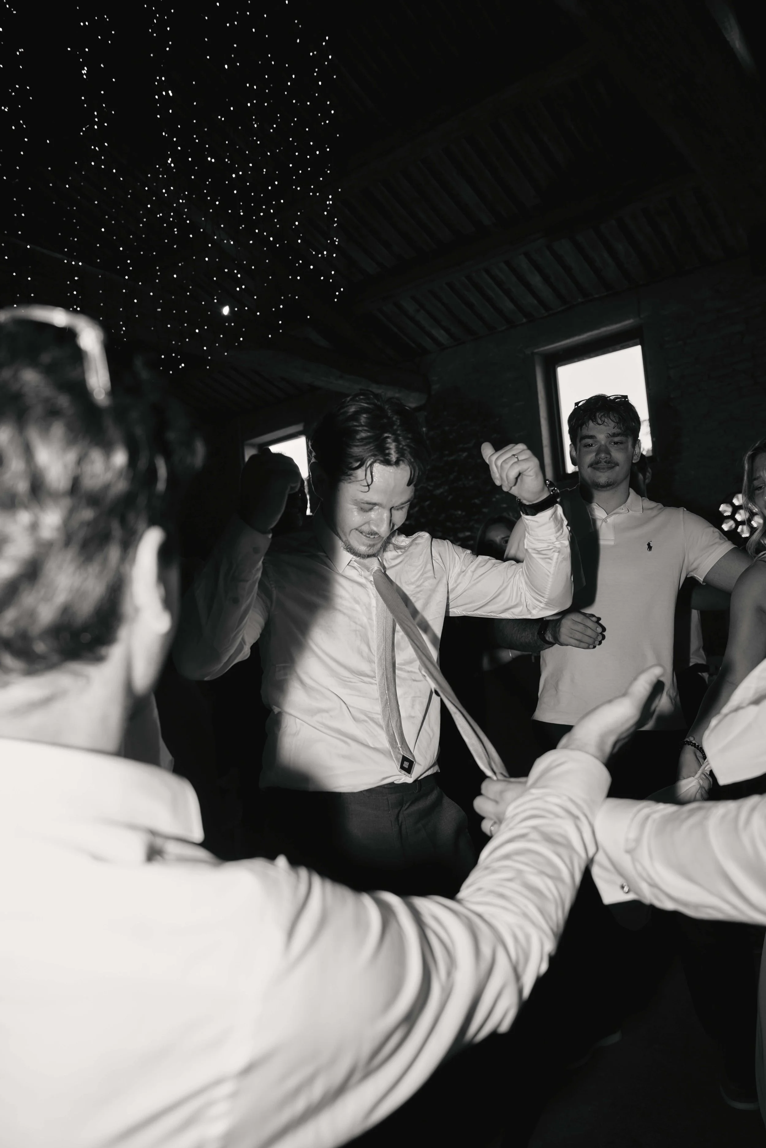 Group of young men dancing and having fun at a nightclub or party, with a starry ceiling and dark interior.