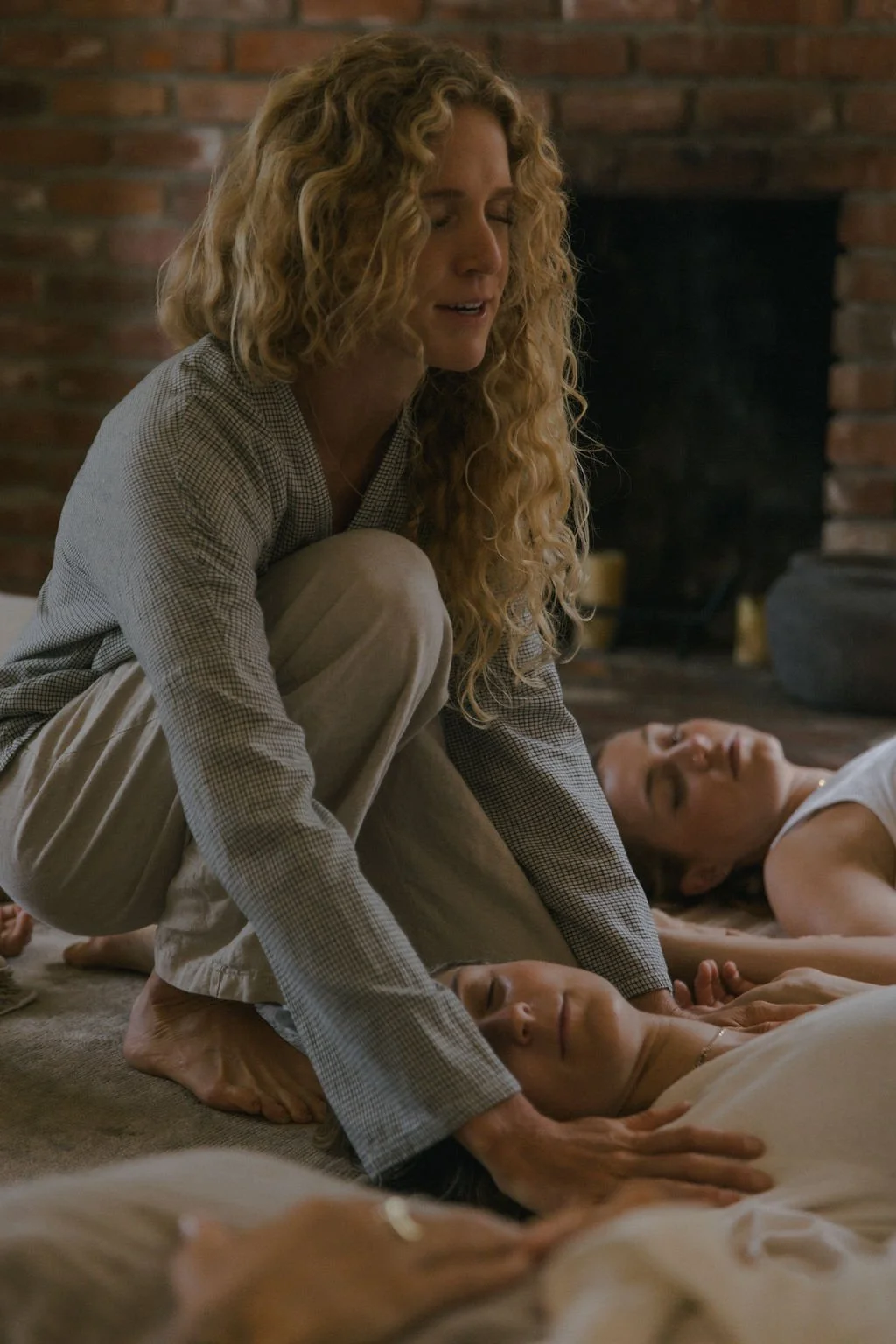 madeleine with curly blonde hair is standing indoors with her hands at a healing workshop