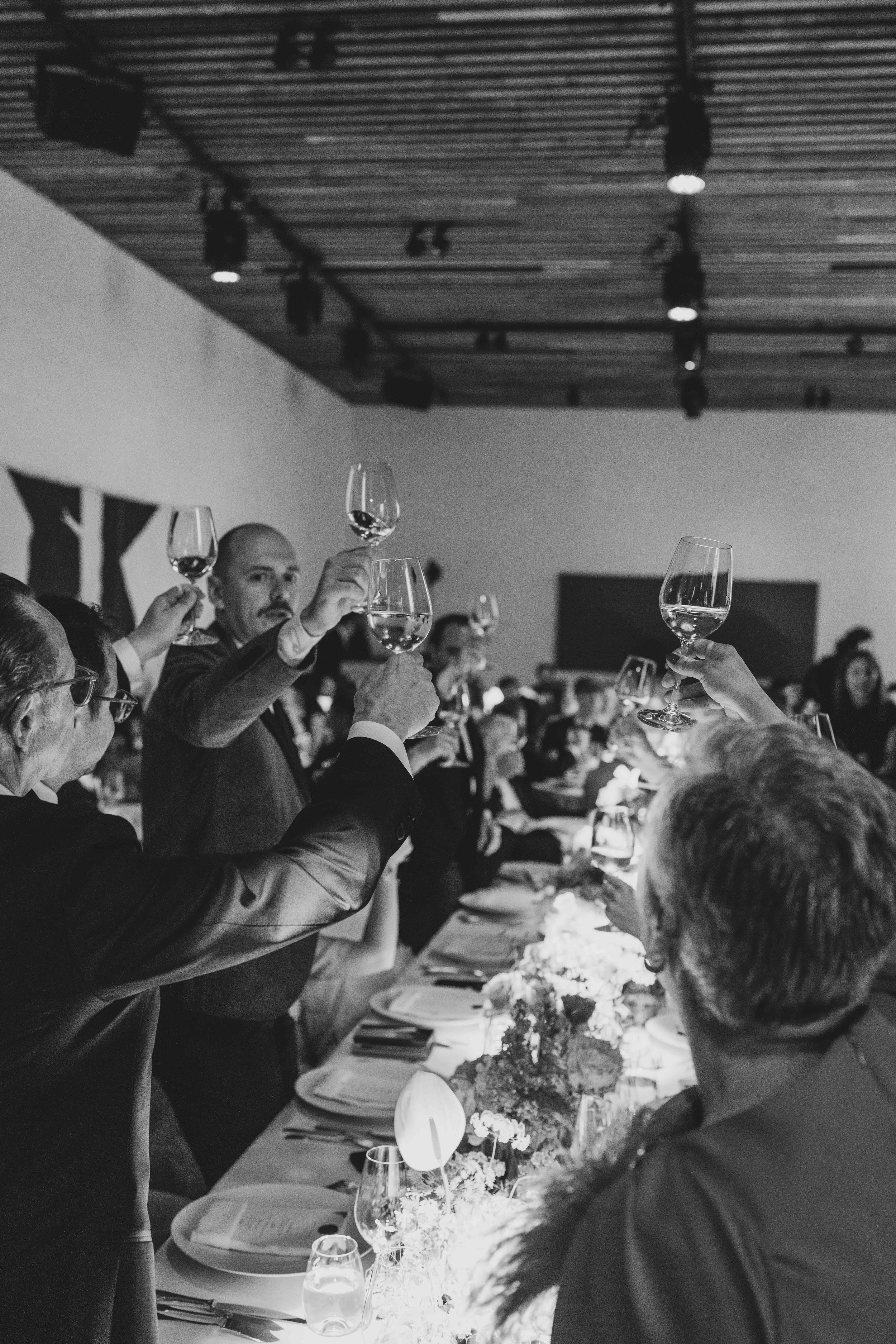 A group of people raising glasses of red wine during a formal dinner event.