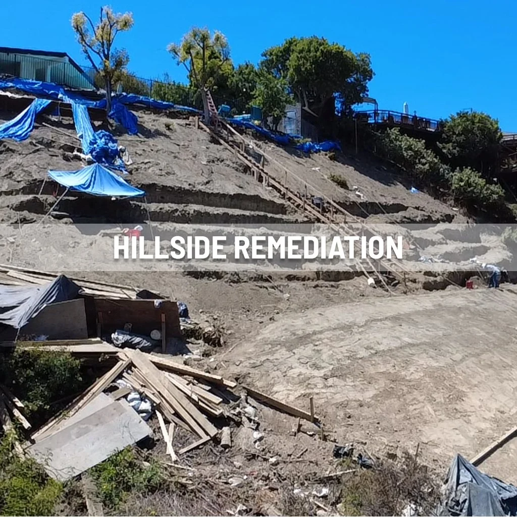 Steep hillside with ongoing remediation work, showing exposed dirt and debris, blue tarps covering parts of the slope, and a staircase or pathway leading up the hill. There are also some trees and structures at the top of the hill.