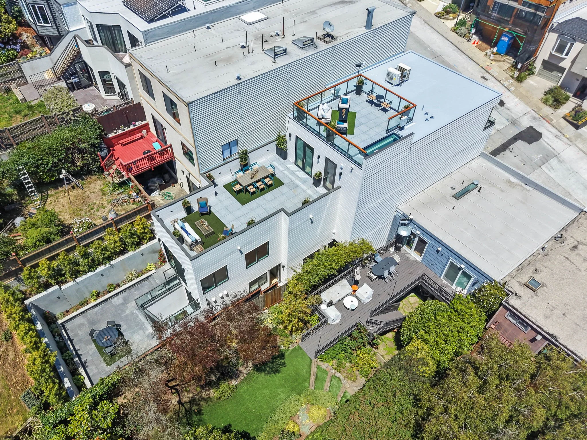 Aerial view of modern houses with rooftop patios, greenery, and a backyard garden.