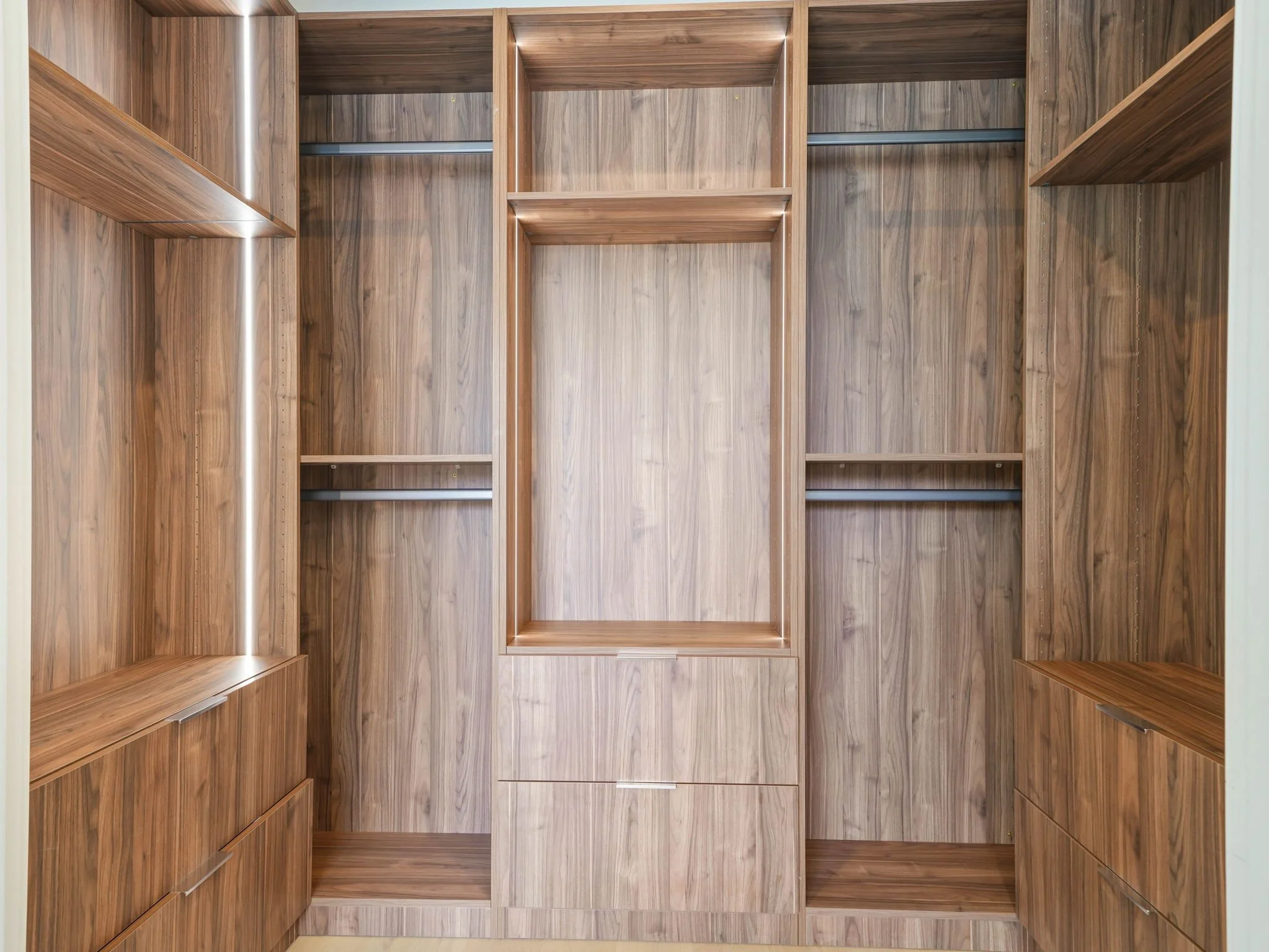 Empty wooden closet with shelves and hanging rods