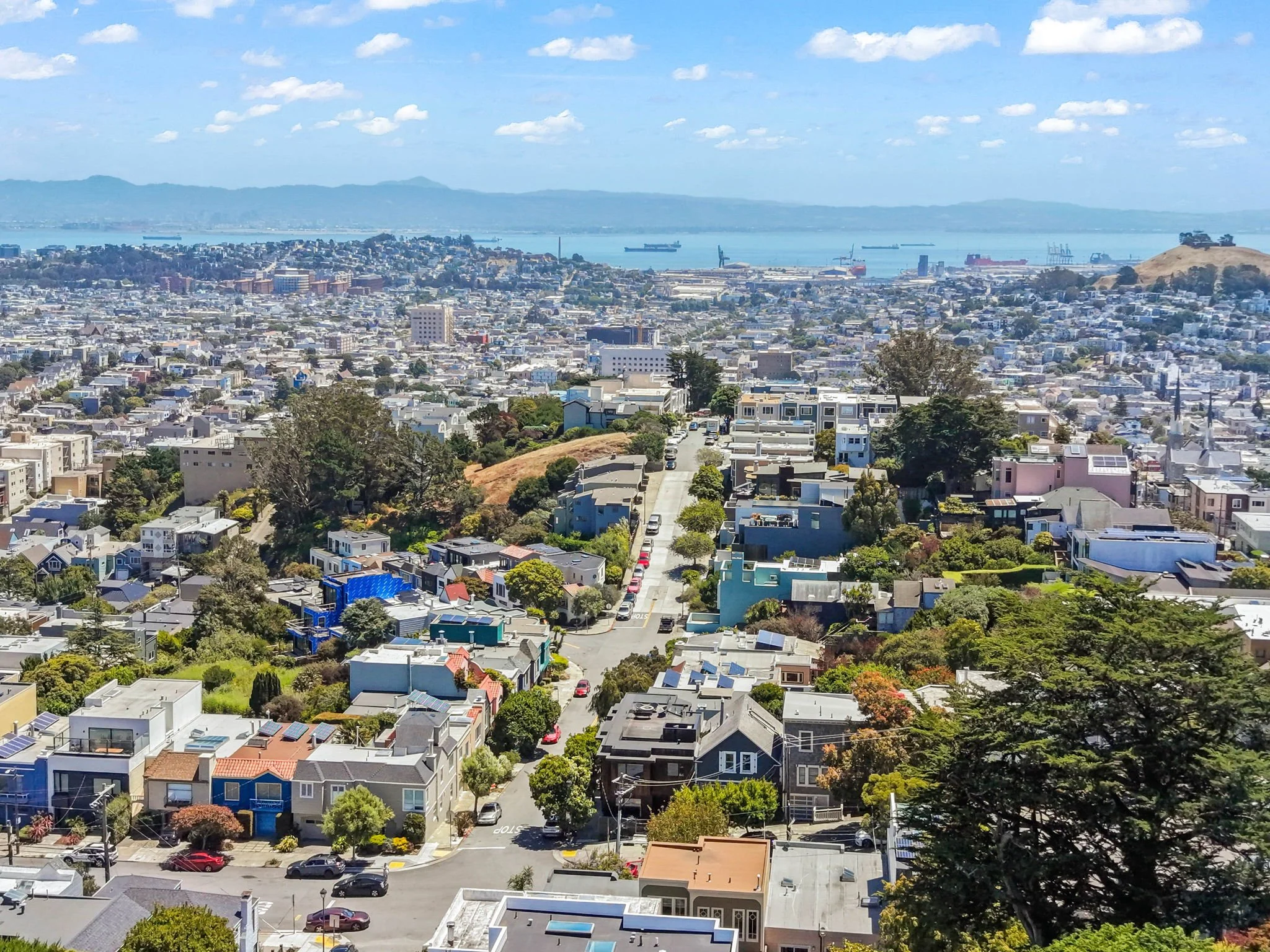 A panoramic view of a city with a water body in the background under a partly cloudy sky.