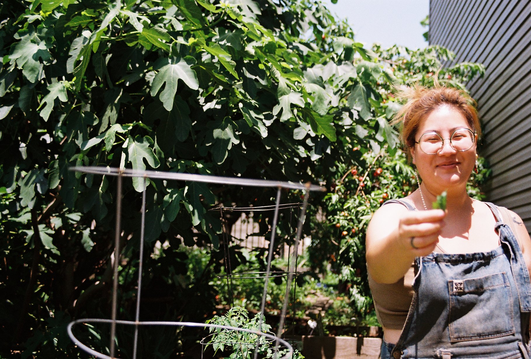 Esther holding out a basil leaf in a garden