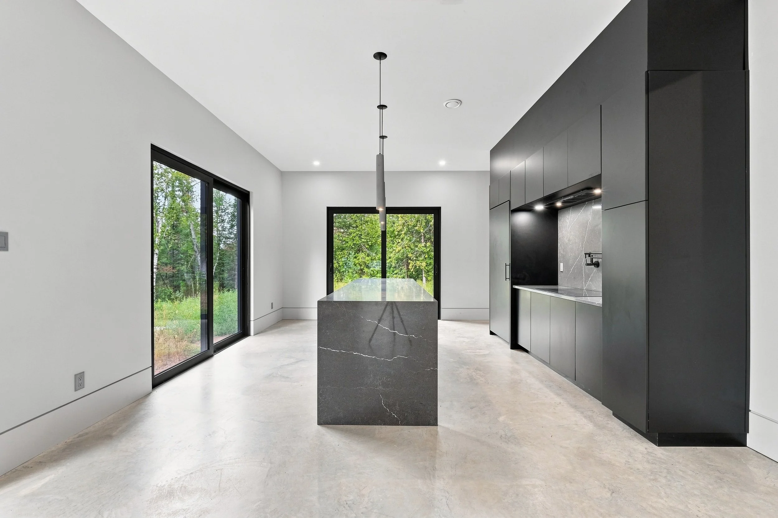 Black and gray kitchen with marble island and large windows, luxury real estate photography in Ottawa