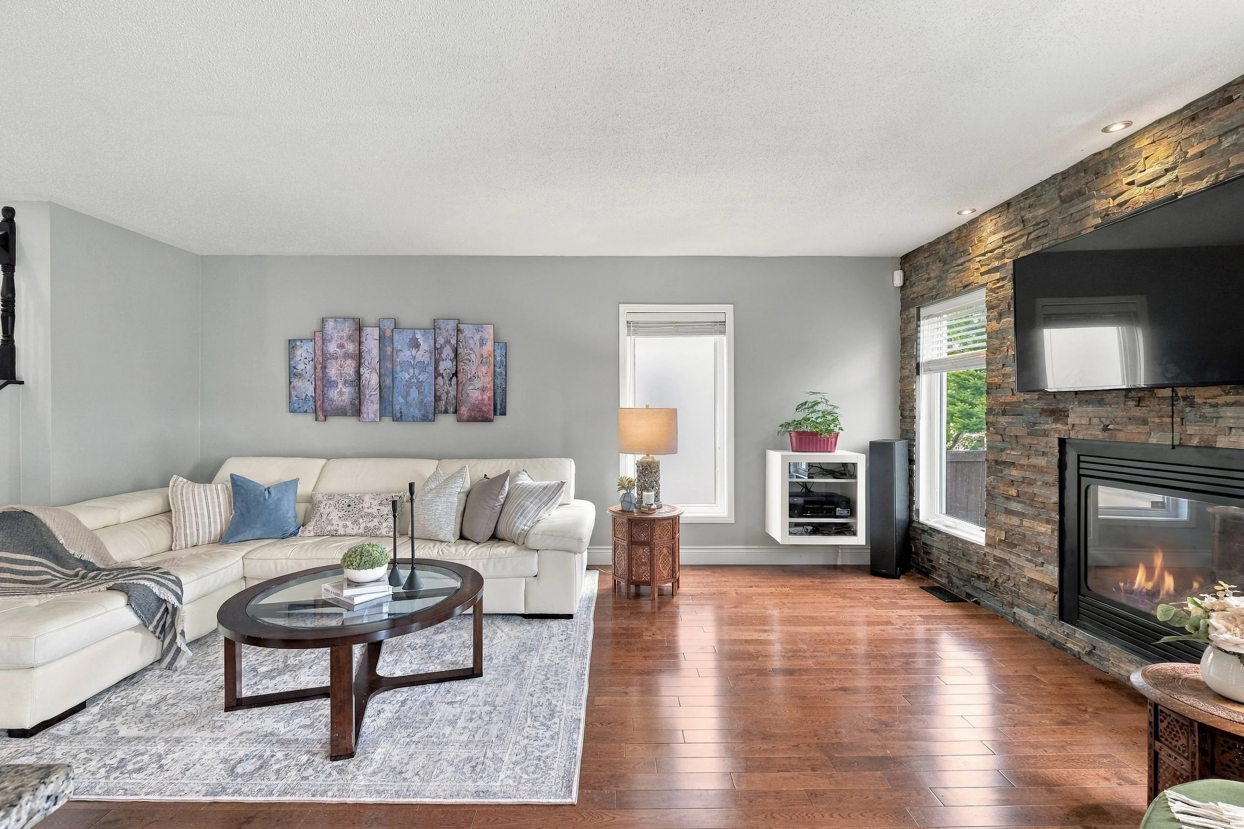 Living room with white sectional and stone fireplace, real estate photographer Ottawa, NewGlimpse
