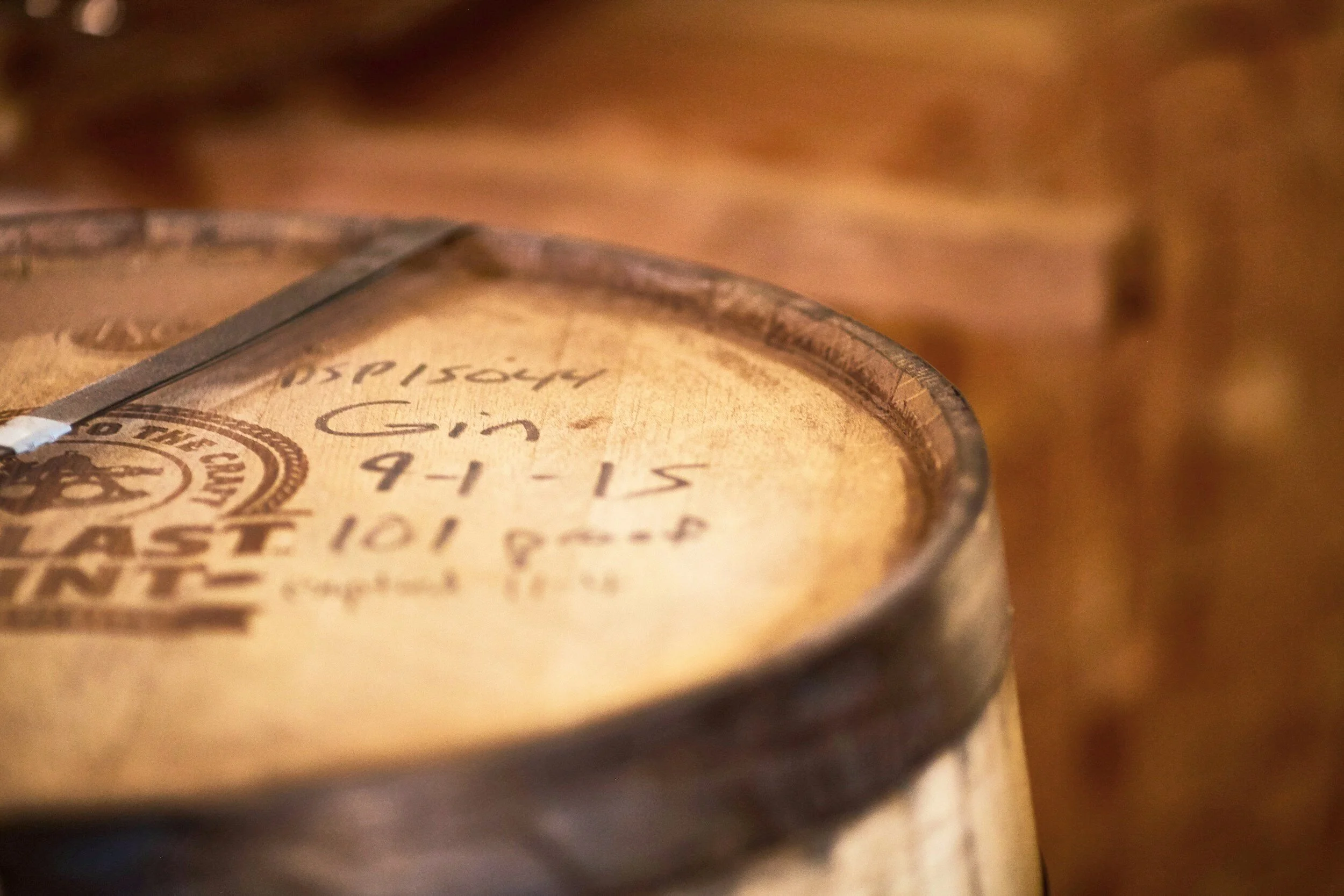 Close-up of a round wooden container with handwritten text on the lid, featuring a metallic knife resting on top.
