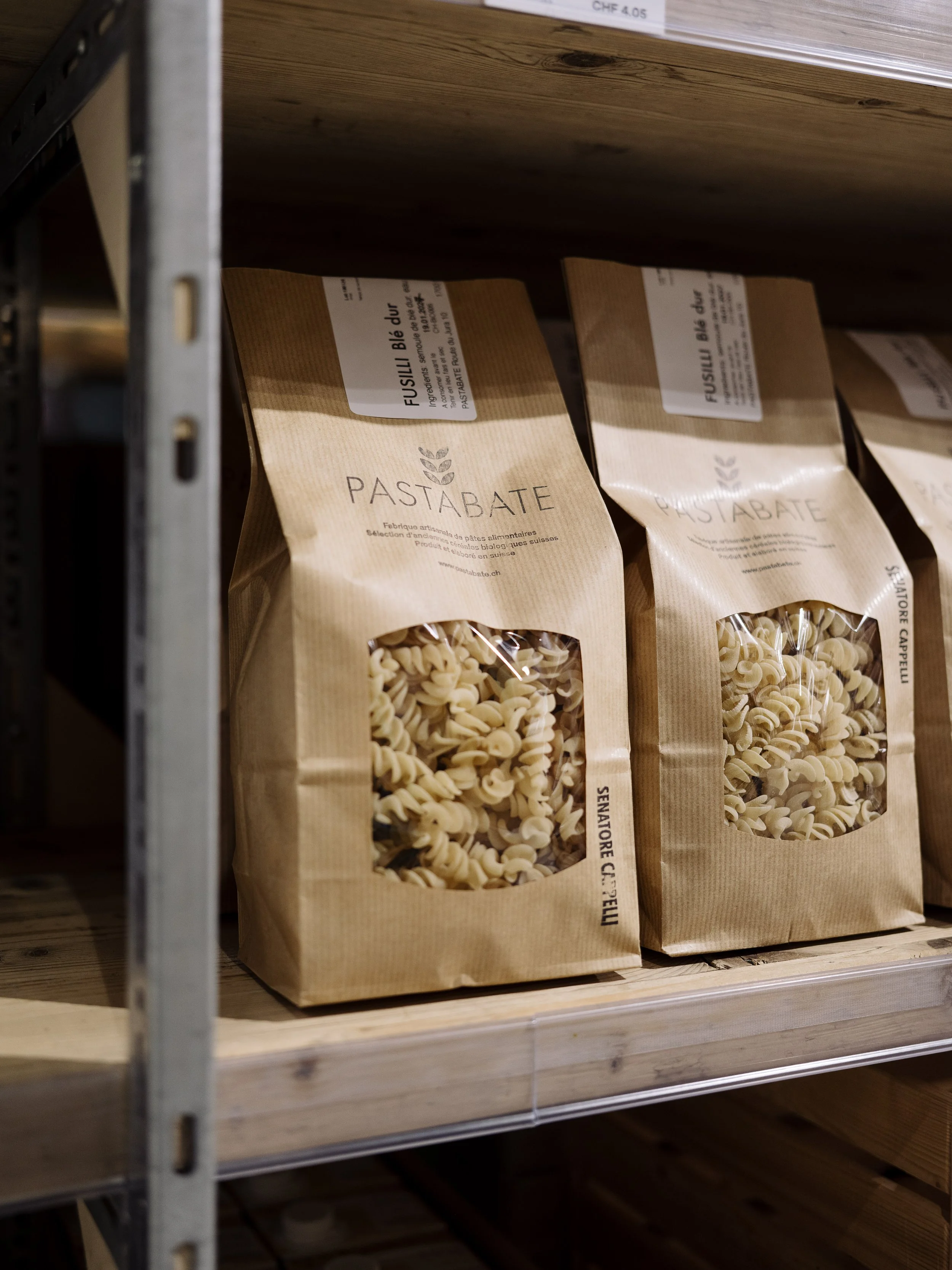 Paquets de fusilli cuillères de pâtes dans un magasin, avec étagère en bois.