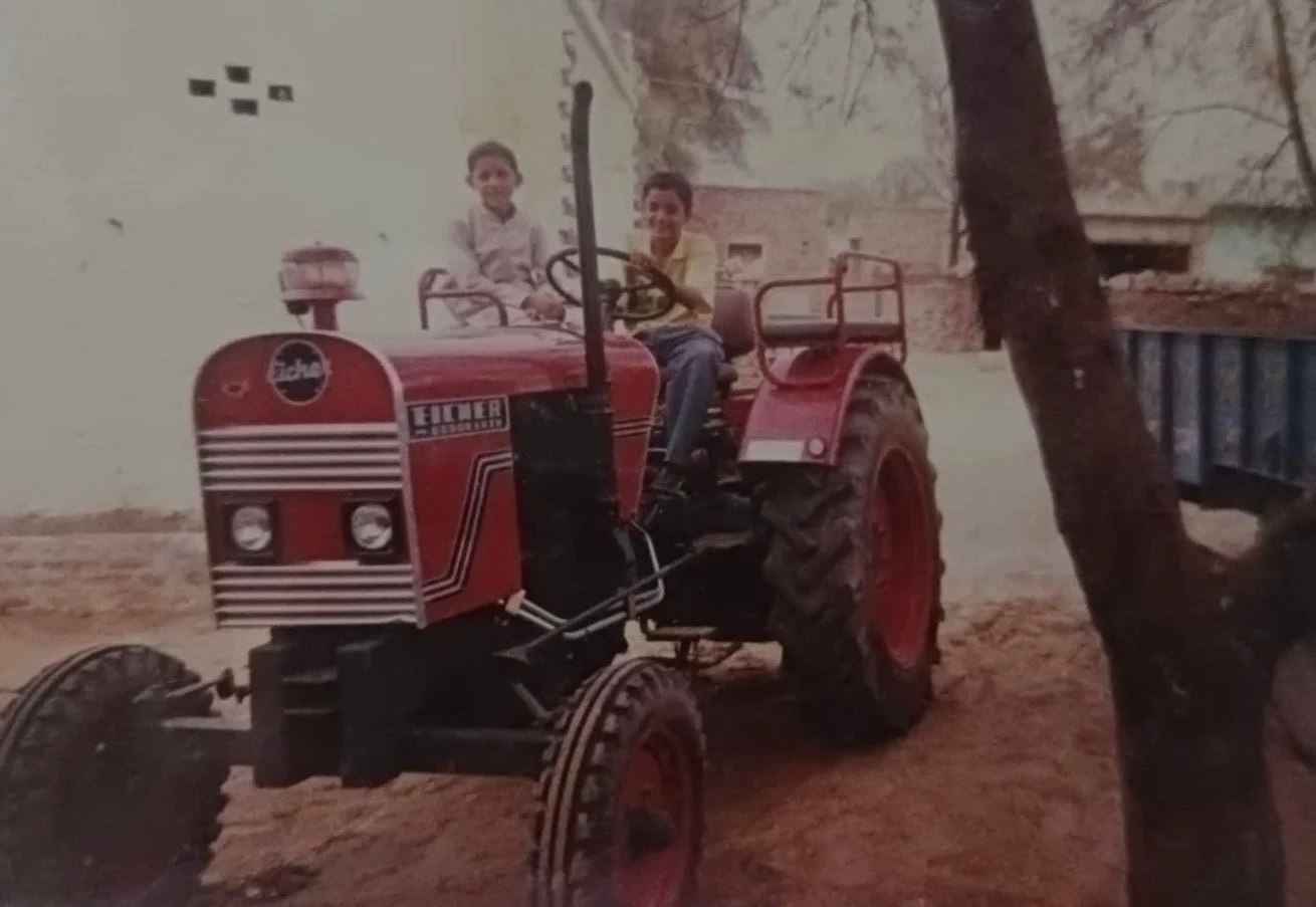 Two boys on a red Eicher tractor in a village in Haryana, India, in the late 1980s. Sanjeev Kumar, aged seven, is at the wheel.