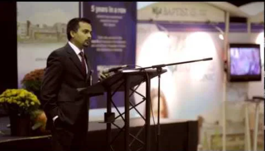 Dr. Kumar in a suit speaking from a podium at a Baptist Memorial Health Care event.