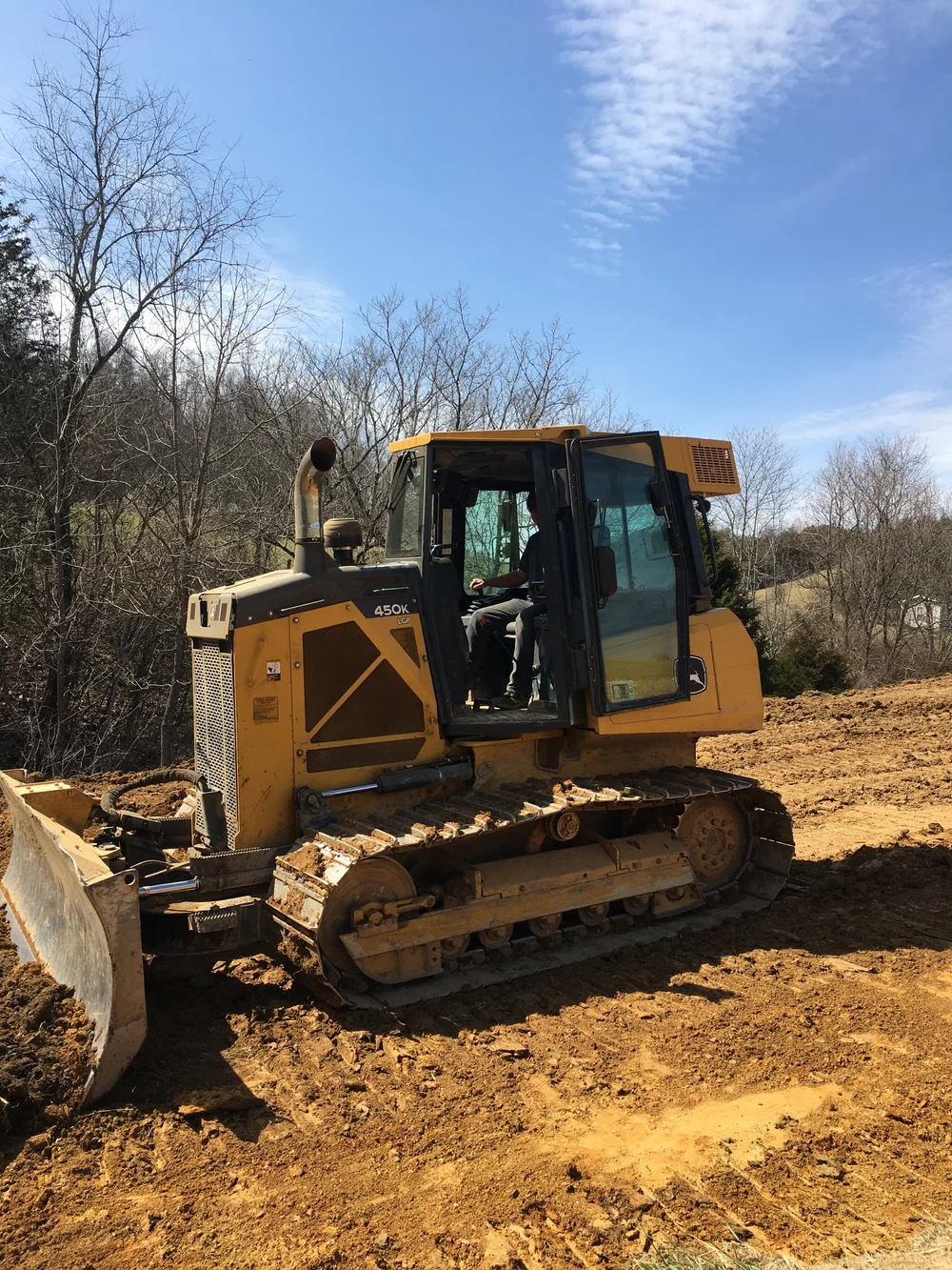 Douglas Vance in the cab of a bulldozer on a cleared hillside