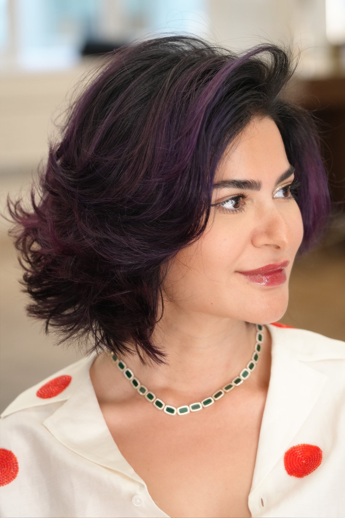 Woman with short, layered dark hair with soft mahogany highlights, coloured cut and styled by Aytaç Özbay.