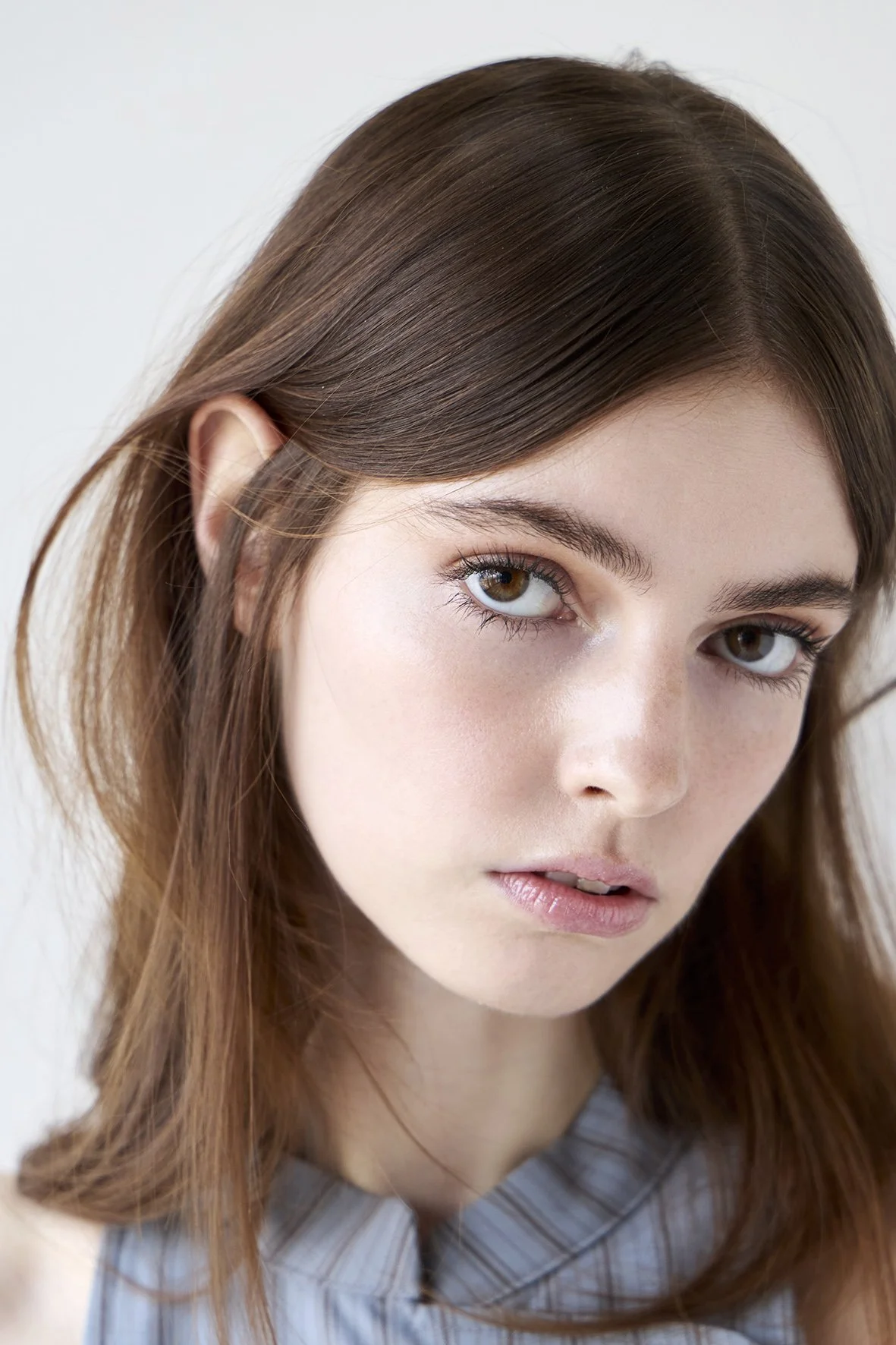 Close-up of a woman with hazelnut brown hair, with a smooth finish blow dry by Domenico Sansone.