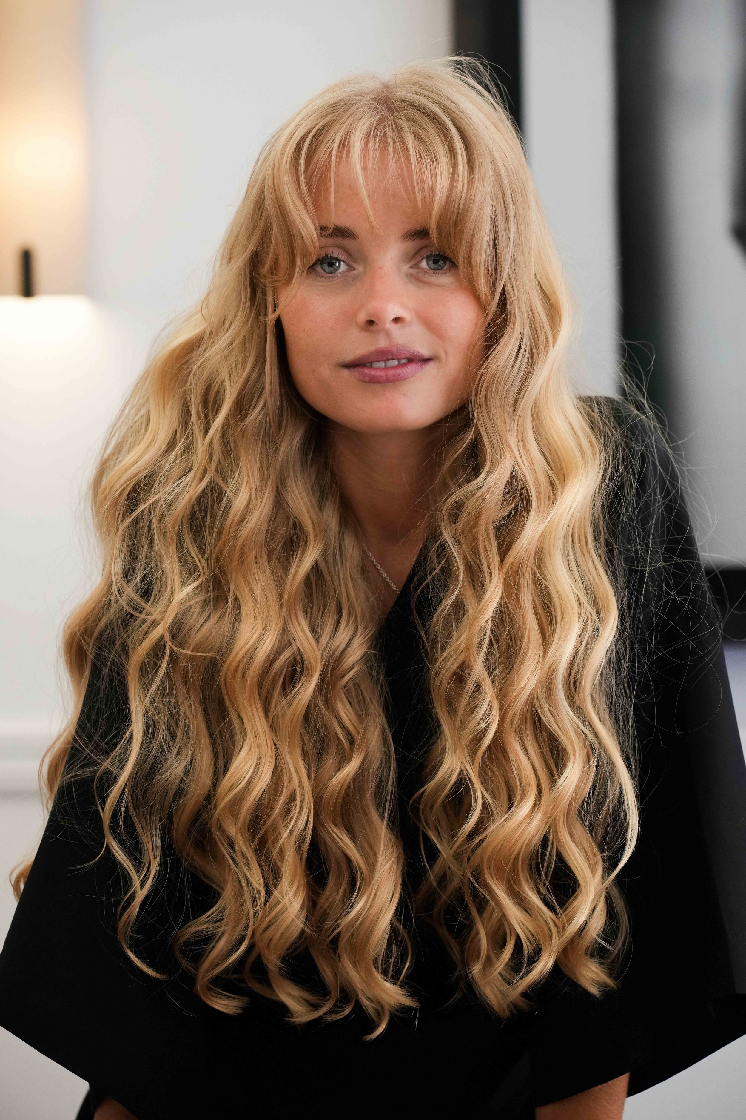Close-up of a woman with long, wavy blonde highlights hair by Milena Kochs.