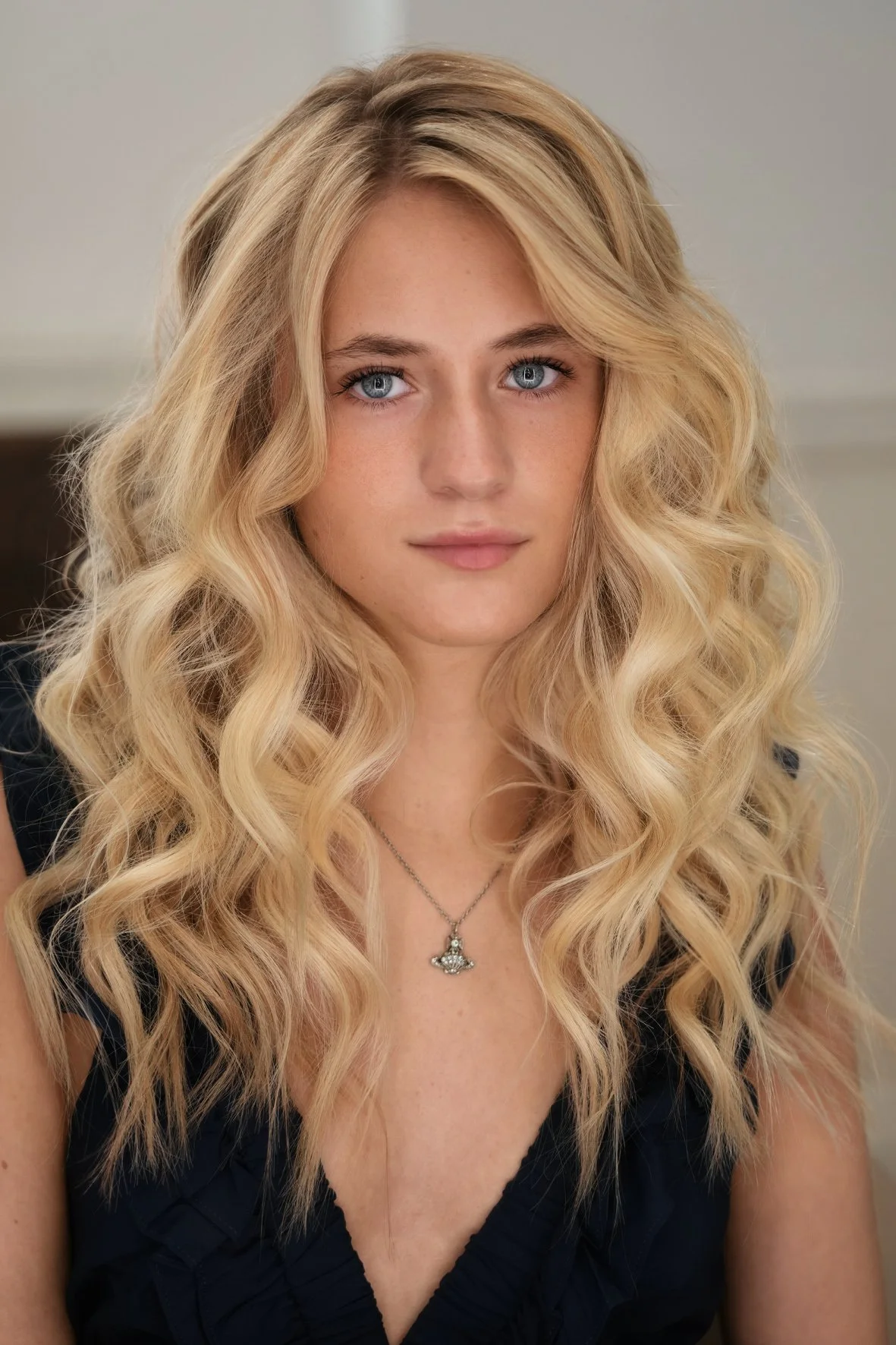 Close-up of a young woman with long, blonde highlights hair colour and a bouncy blow dry finish.