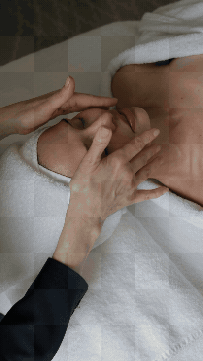 Close-up of a person receiving a facial massage from a therapist in a spa setting.