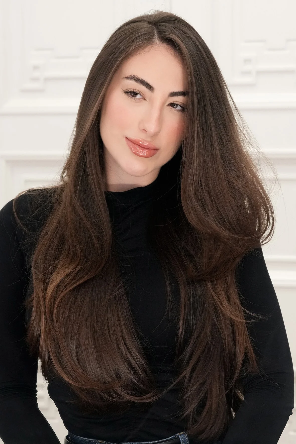 A young woman with long, wavy hair, coloured with a rich expensive brunette hair colour.