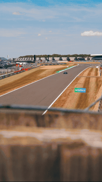 A car racing on a track at a motorsport event with a crowd in the background.
