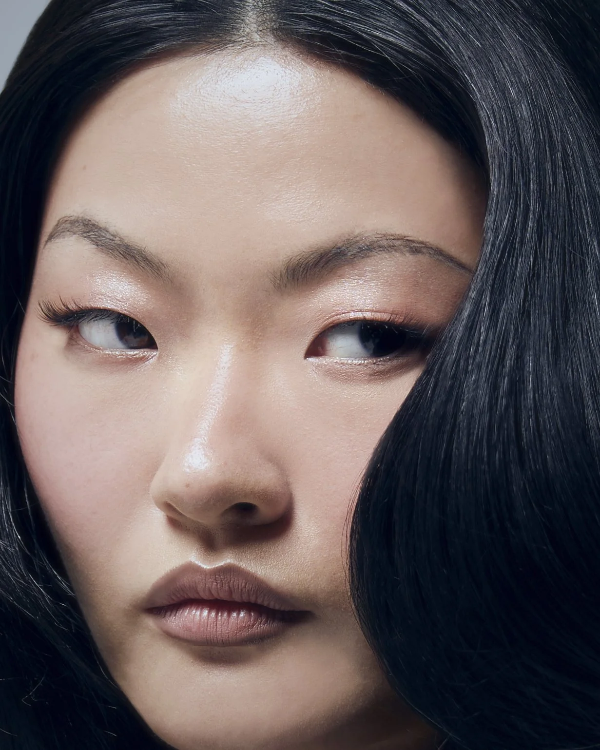 Close-up of a woman's face with smooth skin, and smooth dark hair finish by Domenico Sansone, at The Six, Mayfair.