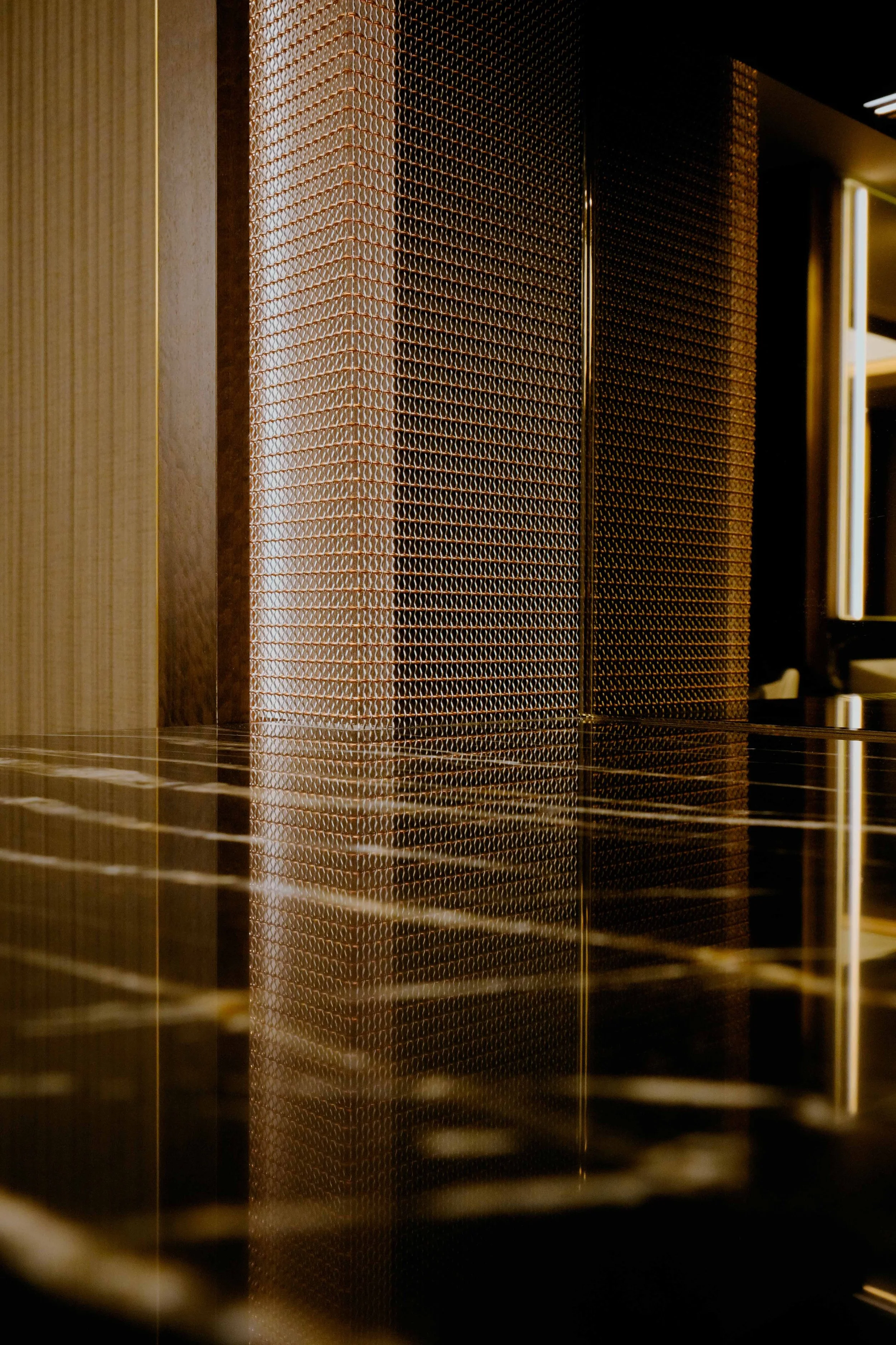 Close-up of a textured golden metallic partition with reflections on a dark, shiny surface.