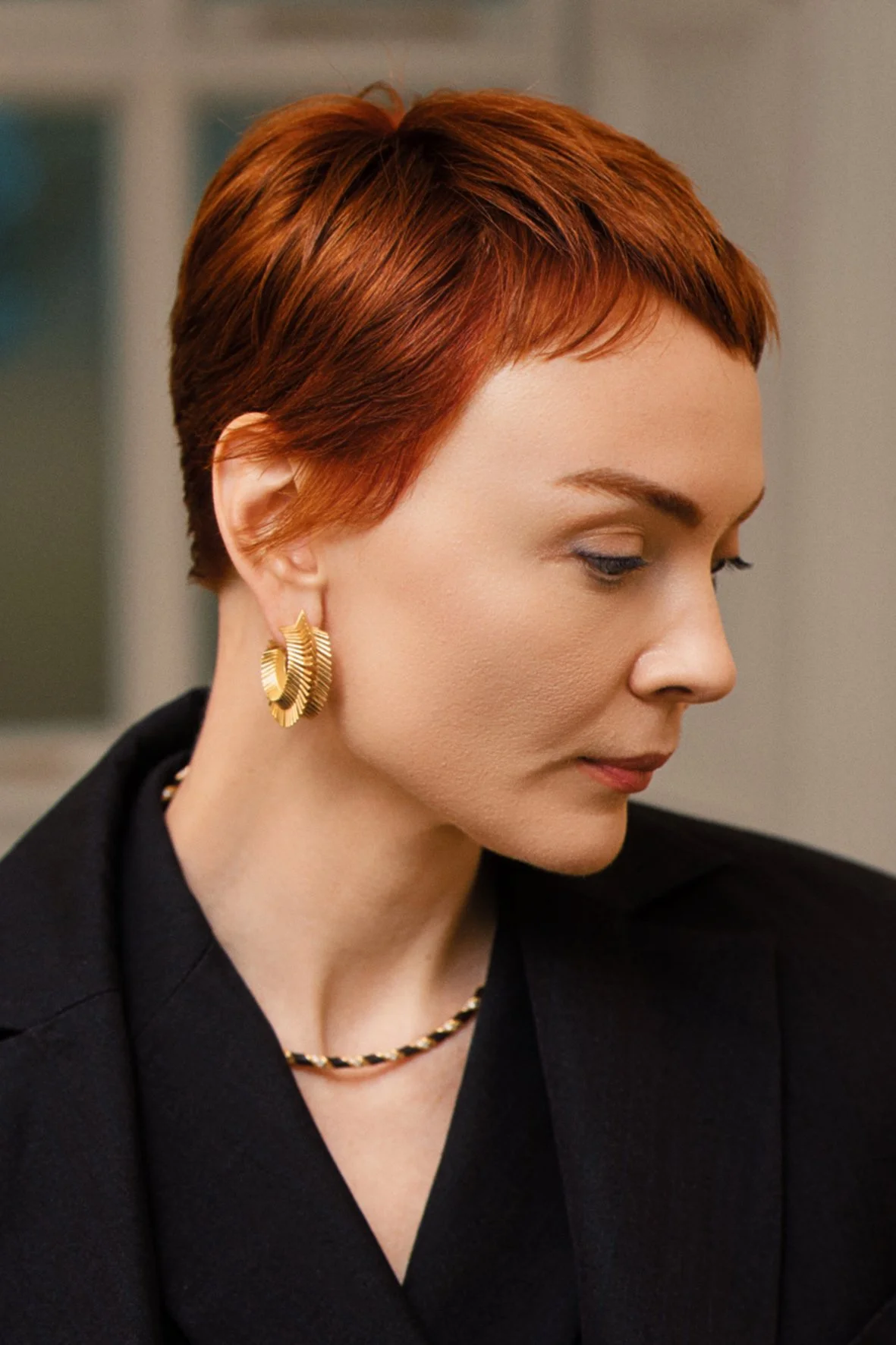 A woman with short, red hair styled in a modern, pixie haircut.