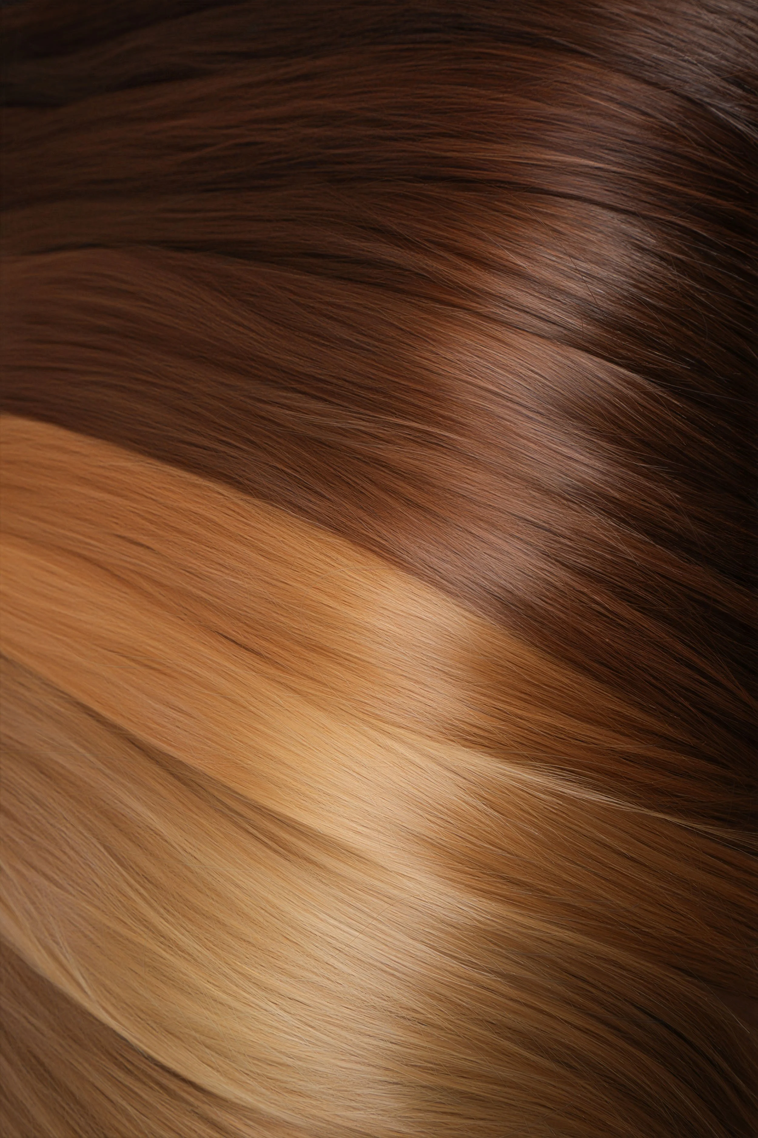 Close-up of smooth, shiny, layered brown and blonde hair extensions hair.